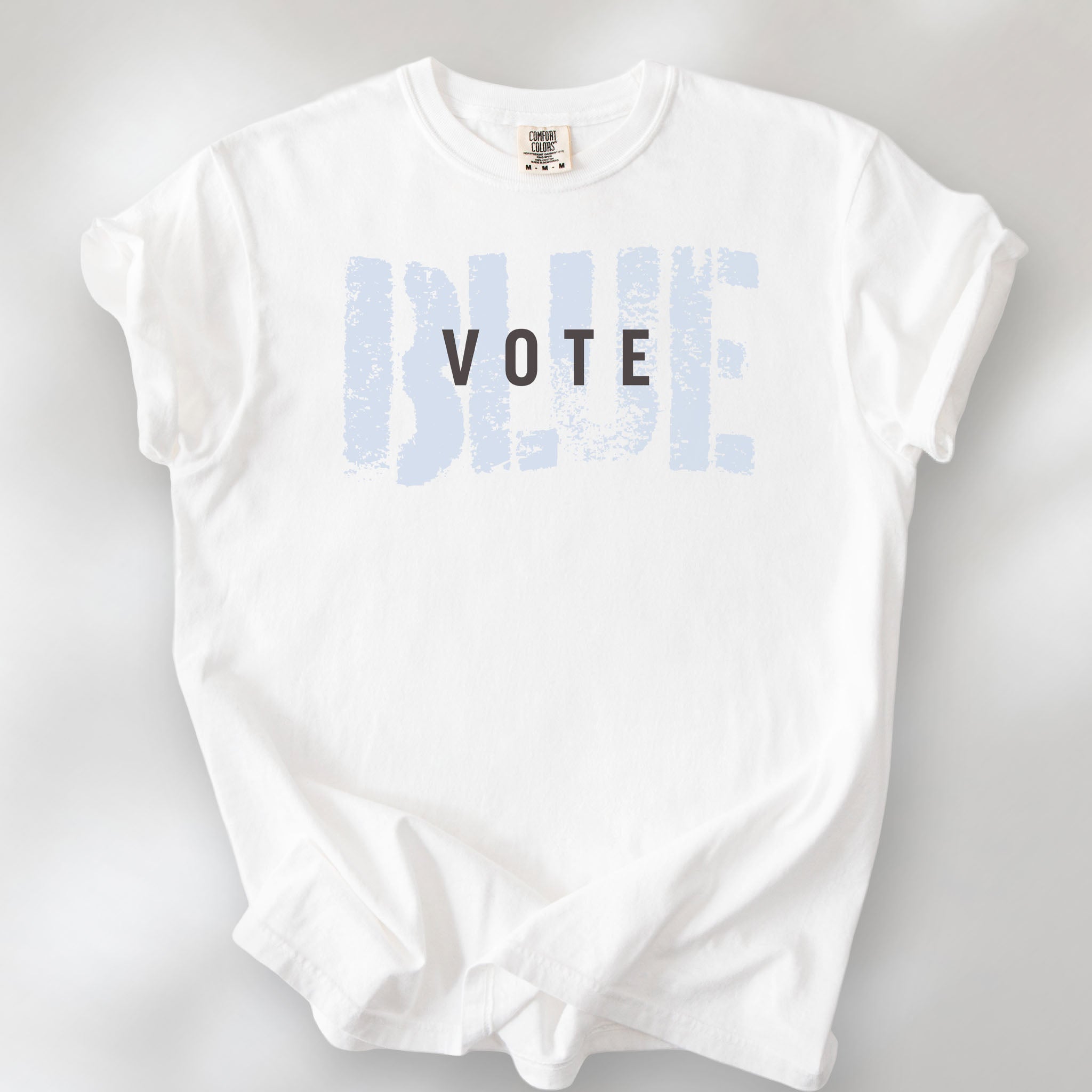 White t-shirt with the word "vote" atop the word "blue" in a grunge background texture.