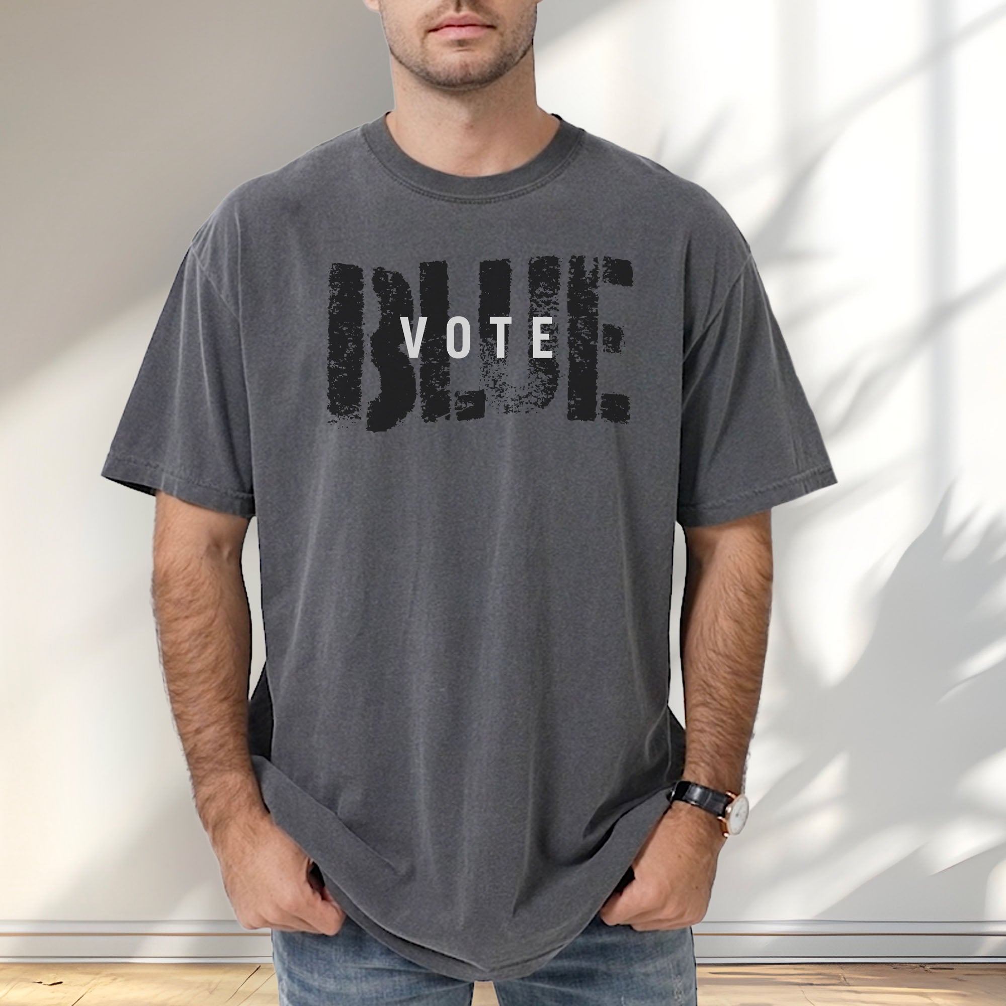 Male model wearing pepper t-shirt with the word "vote" atop the word "blue" in a grunge background texture.