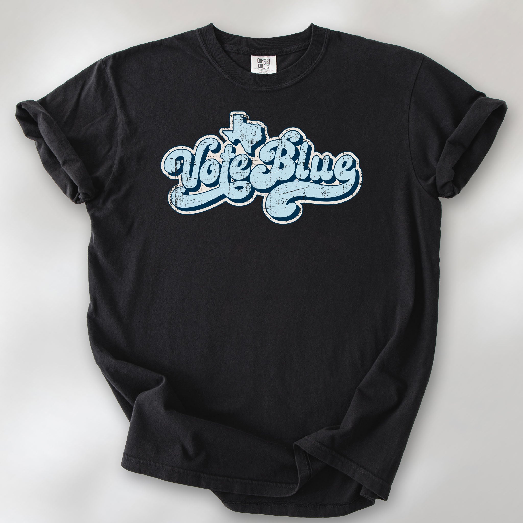 Black t-shirt featuring distressed retro "Vote Blue" script lettering with the outline of Texas above the design.