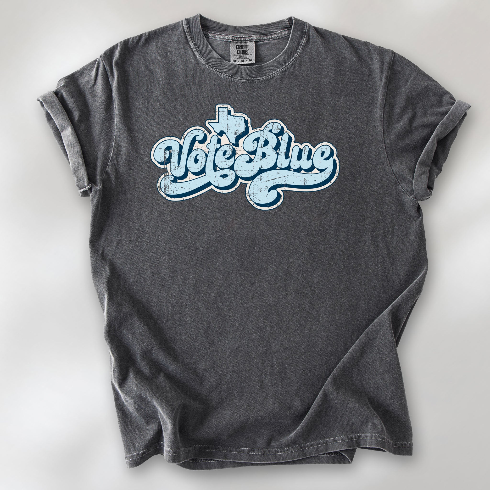 Pepper t-shirt featuring distressed retro "Vote Blue" script lettering with the outline of Texas above the design.
