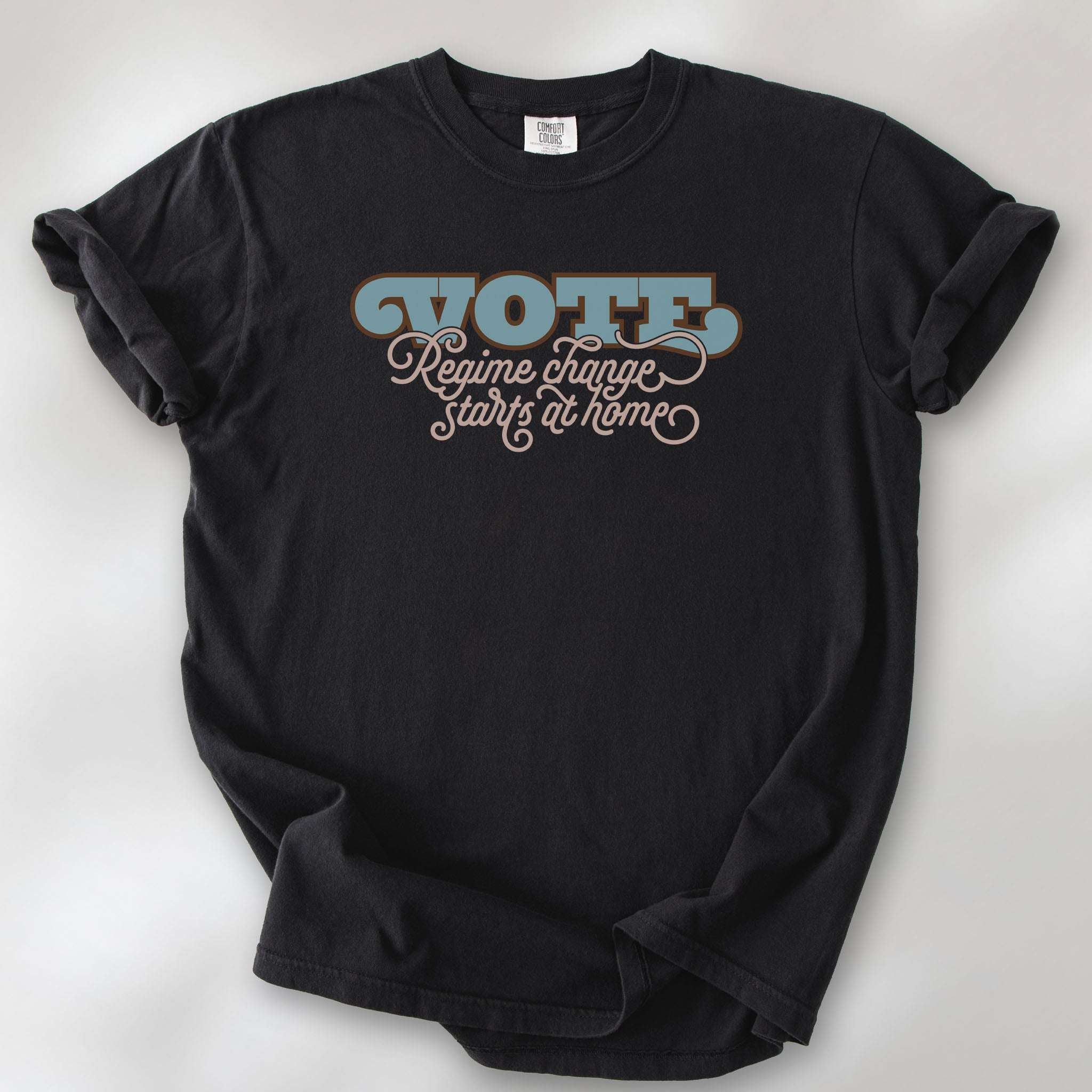 Black t-shirt with retro text reading “Vote: Regime Change Starts at Home,” promoting voting and political accountability.