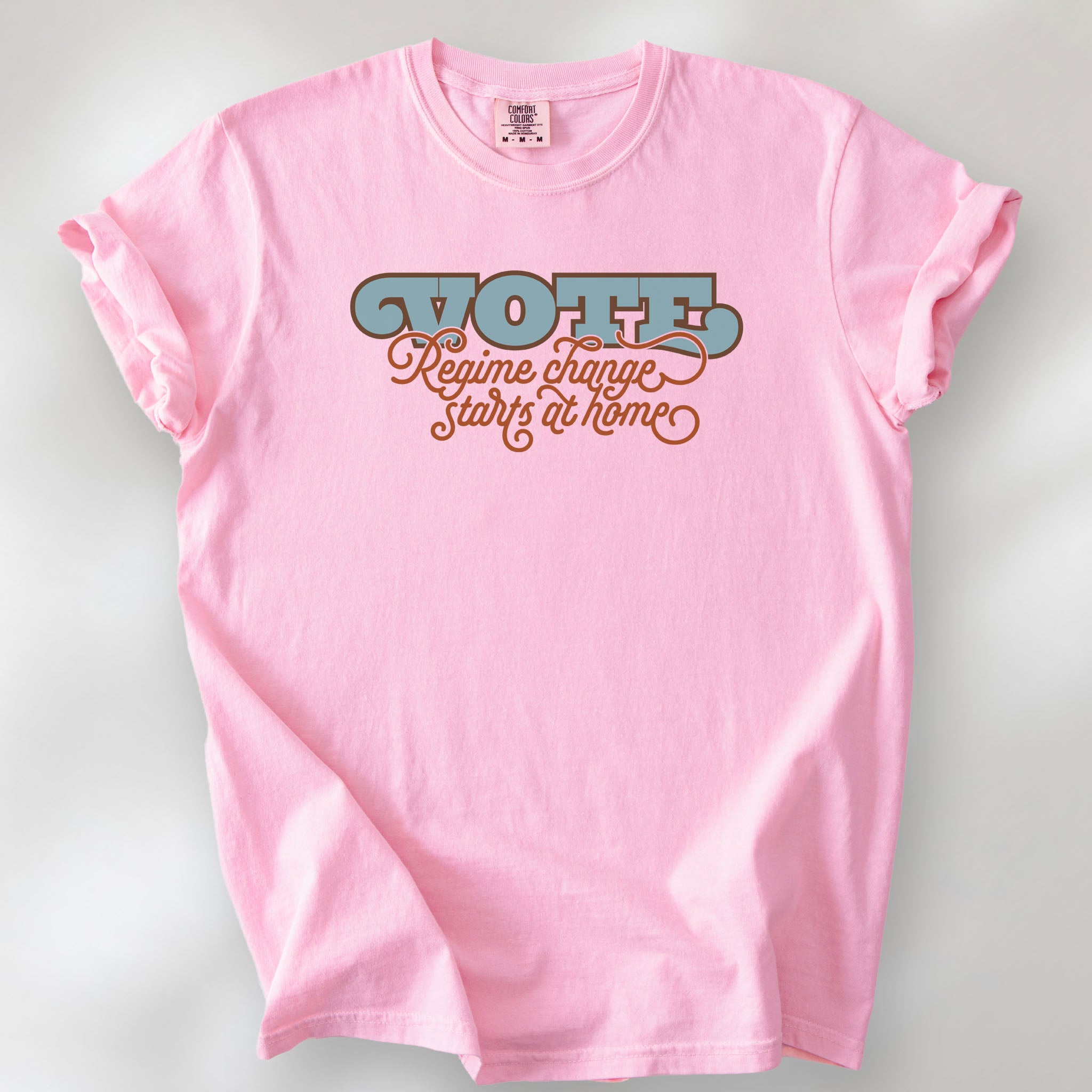 Blossom t-shirt with retro text reading “Vote: Regime Change Starts at Home,” promoting voting and political accountability.
