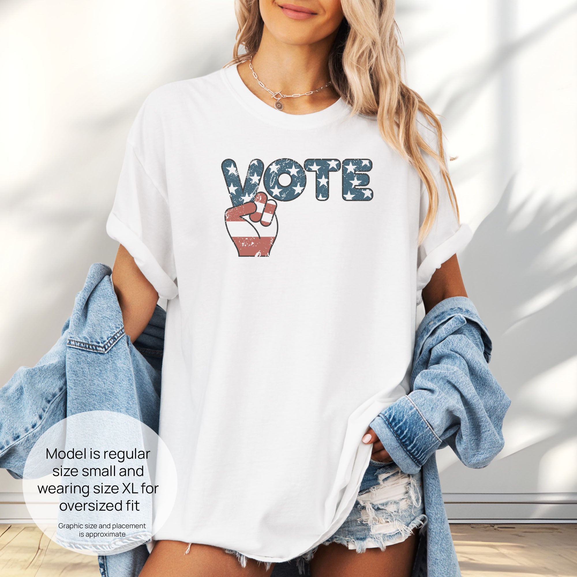 Female model wearing oversized white t-shirt featuring a distressed retro "VOTE" graphic with blue stars and a vintage red and blue hand making a peace sign. Includes size and fit information for the model who is regular size small, and wearing a size XL shirt for an oversized fit.
