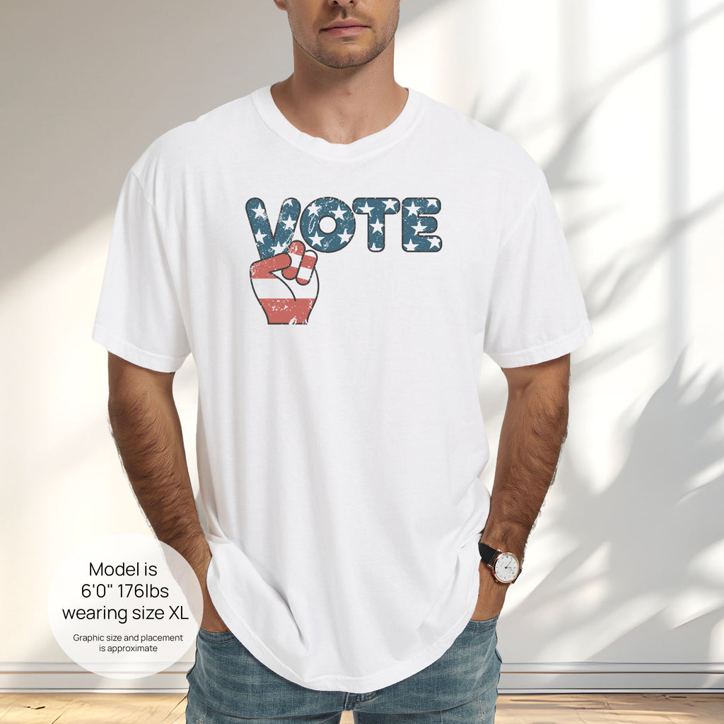 Male model wearing white t-shirt featuring a distressed retro "VOTE" graphic with blue stars and a vintage red and blue hand making a peace sign. Includes size and fit information for the model who is 6 feet 0 inches, 176 pounds, and wearing a size XL shirt.

