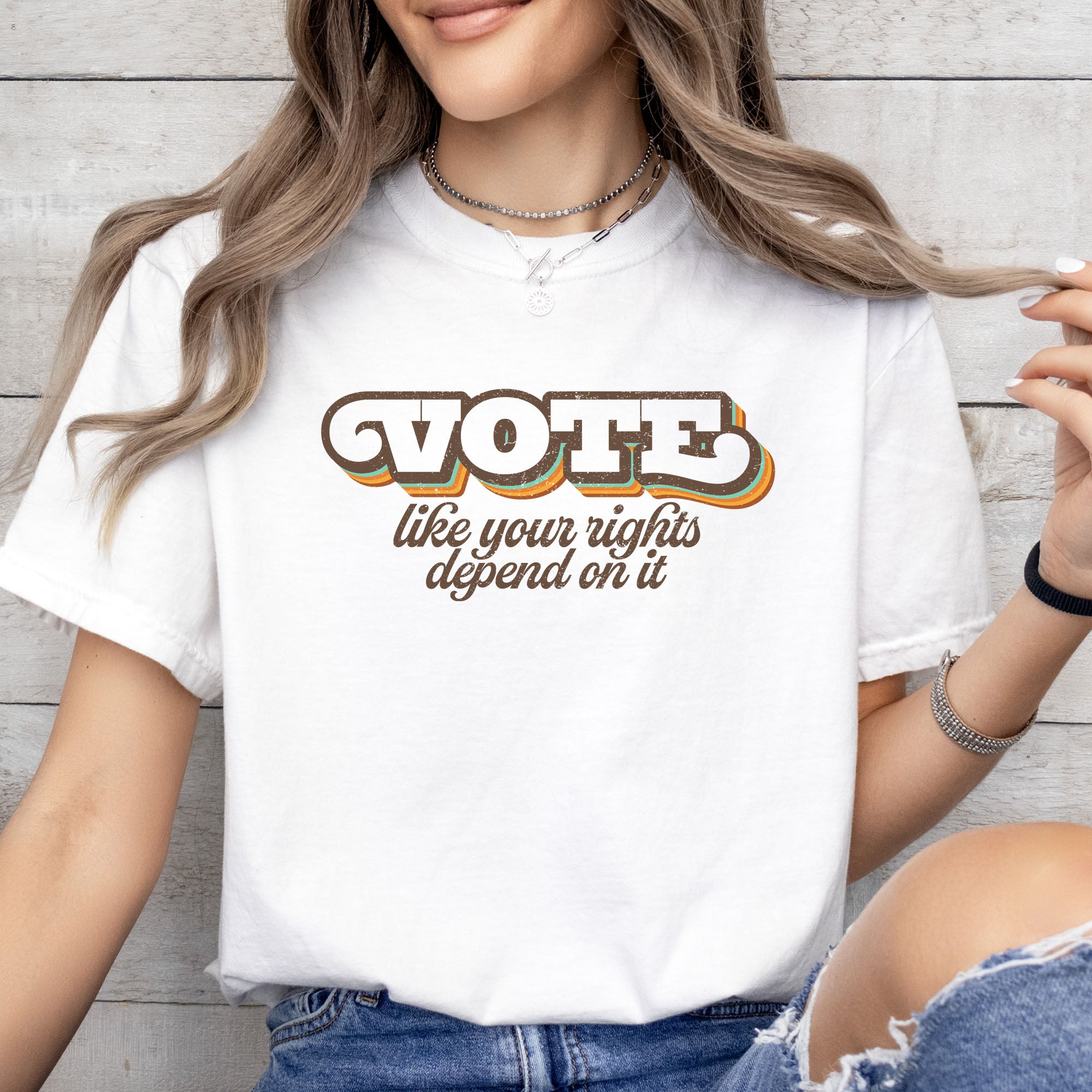 Female model wearing white t-shirt reading “VOTE like your rights depend on it” in a retro stylized text block for everyday political activism and progressive voting rights advocacy.