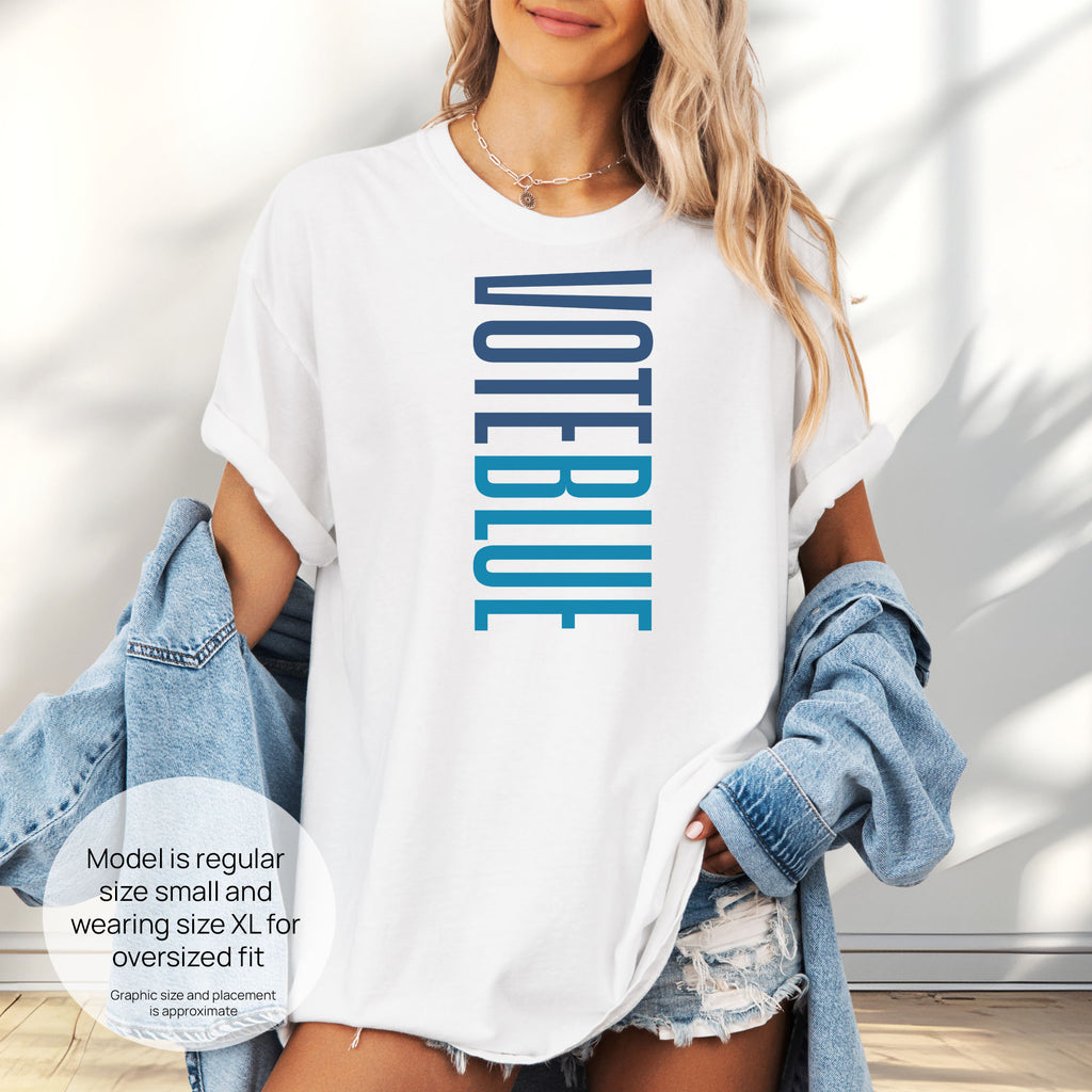 Female model wearing oversized white t-shirt featuring the words "VOTE BLUE" stacked vertically in bold minimalist blue typography. Includes size and fit information for the model who is 6 feet 0 inches, 176 pounds, and wearing a size XL shirt.
