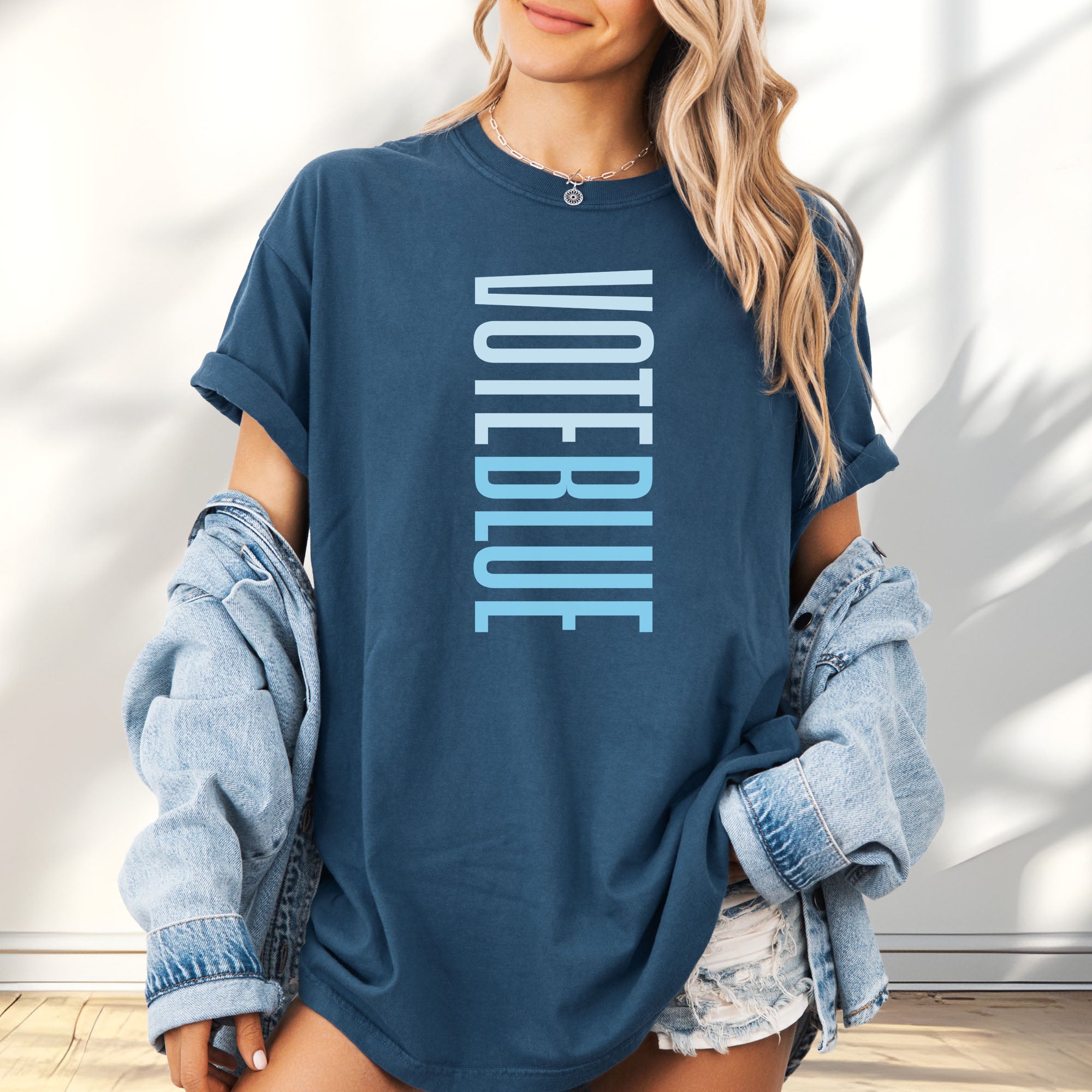 Female model wearing oversized midnight t-shirt featuring the words "VOTE BLUE" stacked vertically in bold minimalist blue typography.