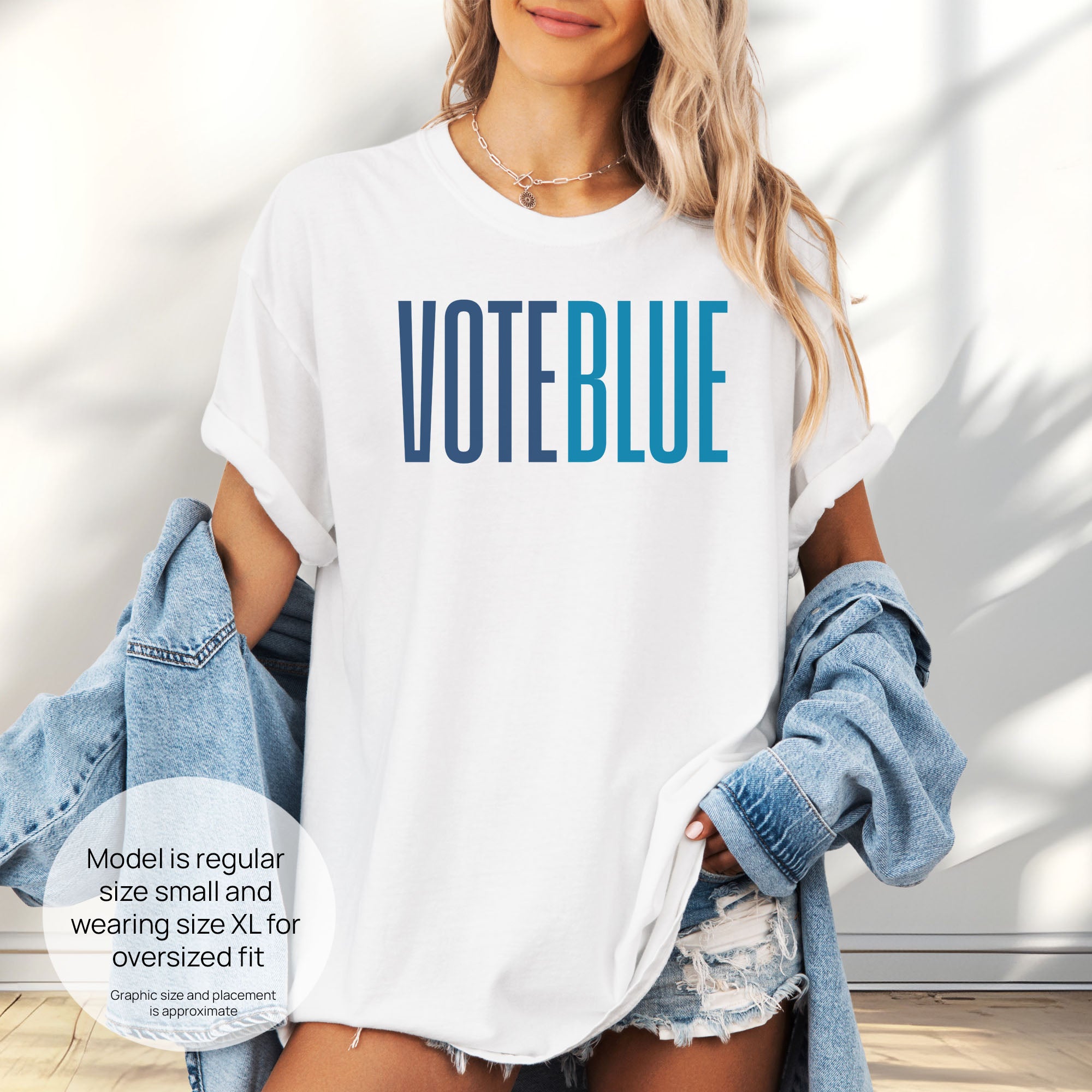 Female model wearing oversized white t-shirt featuring the words "VOTE BLUE" in bold horizontal blue geometric typography with a clean minimalist design. Includes size and fit information for the model who is regular size small, and wearing a size XL shirt for an oversized fit.
