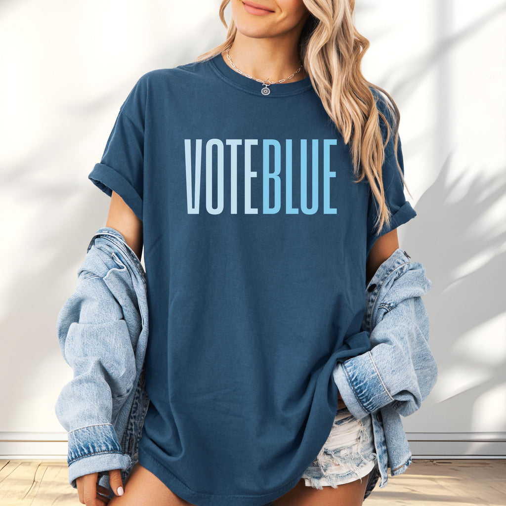 Female model wearing oversized midnight t-shirt featuring the words "VOTE BLUE" in bold horizontal blue geometric typography with a clean minimalist design.