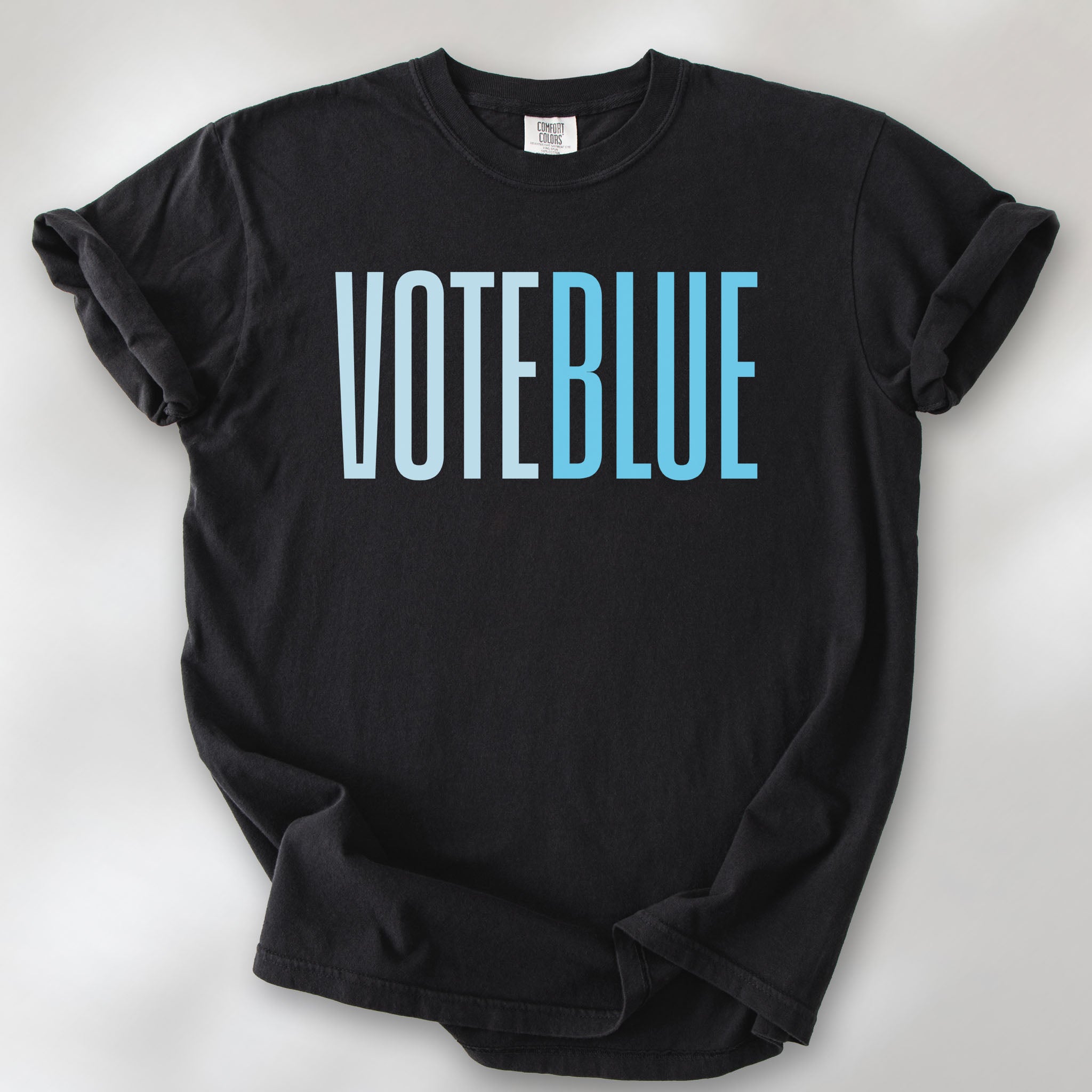 Black t-shirt featuring the words "VOTE BLUE" in bold horizontal blue geometric typography with a clean minimalist design.