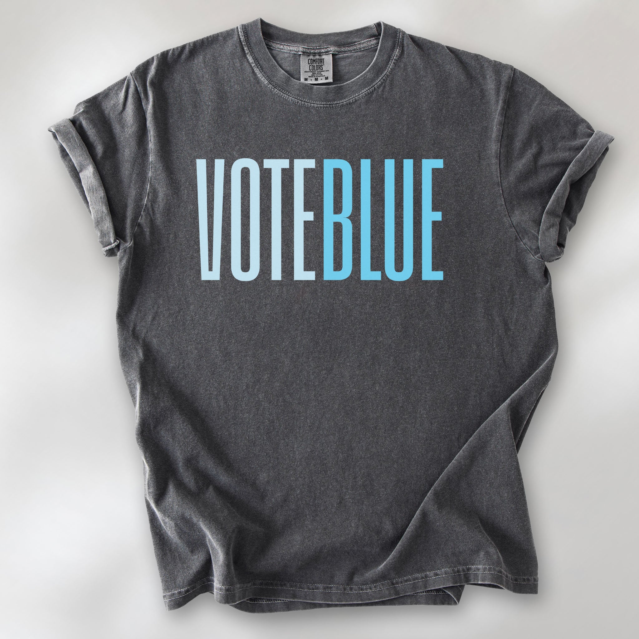 Pepper t-shirt featuring the words "VOTE BLUE" in bold horizontal blue geometric typography with a clean minimalist design.