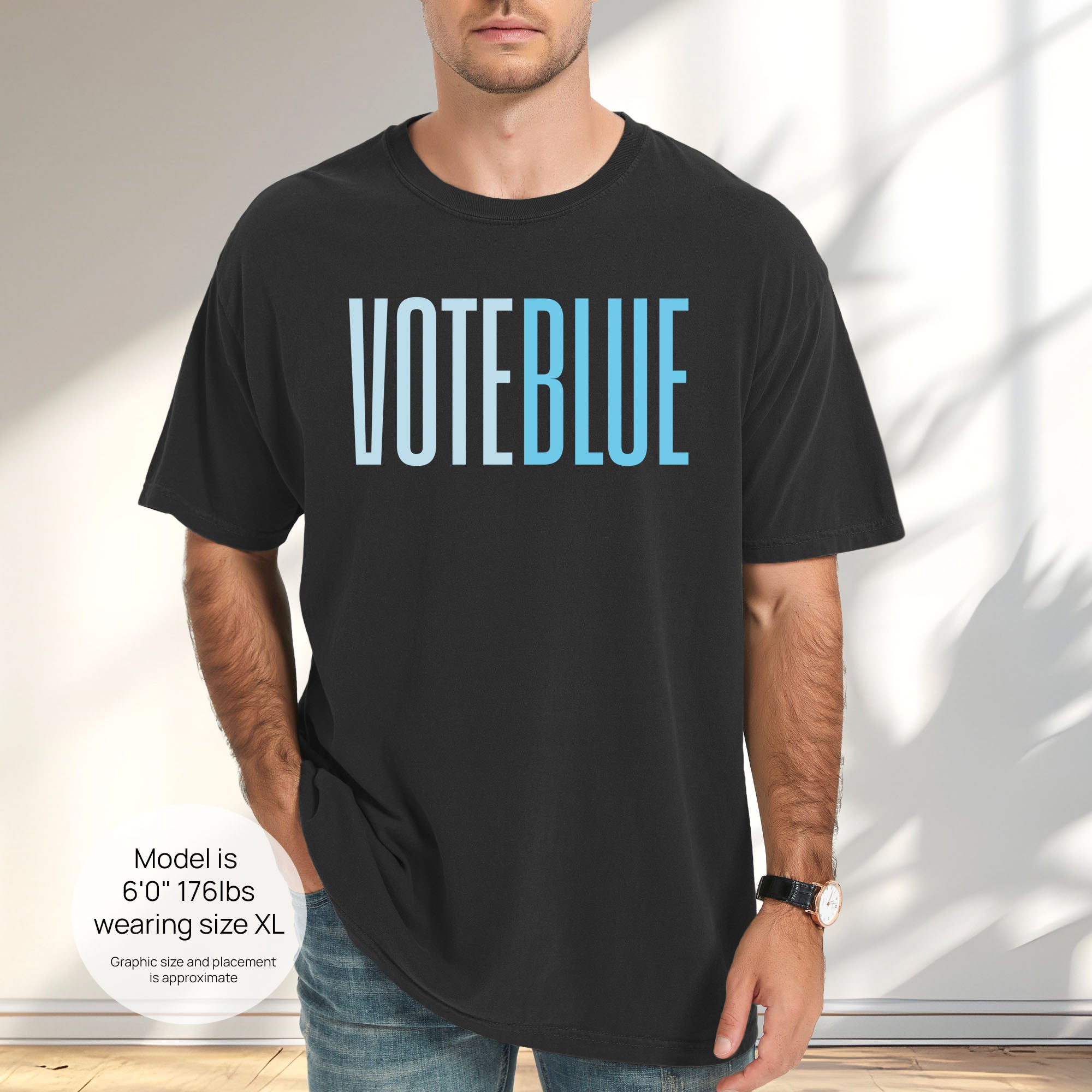Male model wearing black t-shirt featuring the words "VOTE BLUE" in bold horizontal blue geometric typography with a clean minimalist design. Includes size and fit information for the model who is 6 feet 0 inches, 176 pounds, and wearing a size XL shirt.
