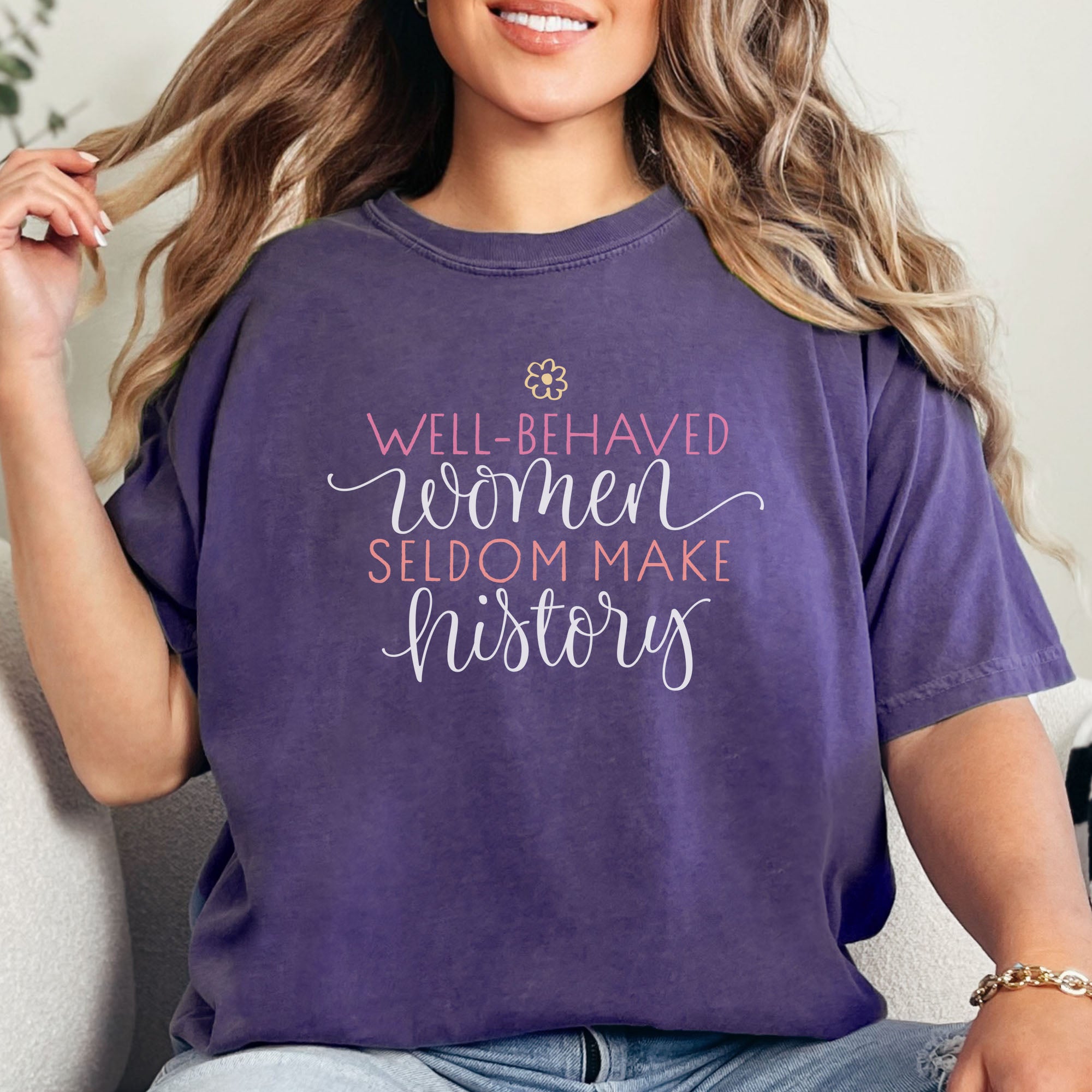 Female model wearing grape feminist t-shirt with colorful text that reads “Well-behaved women seldom make history” — empowering women’s rights shirt and activist apparel.