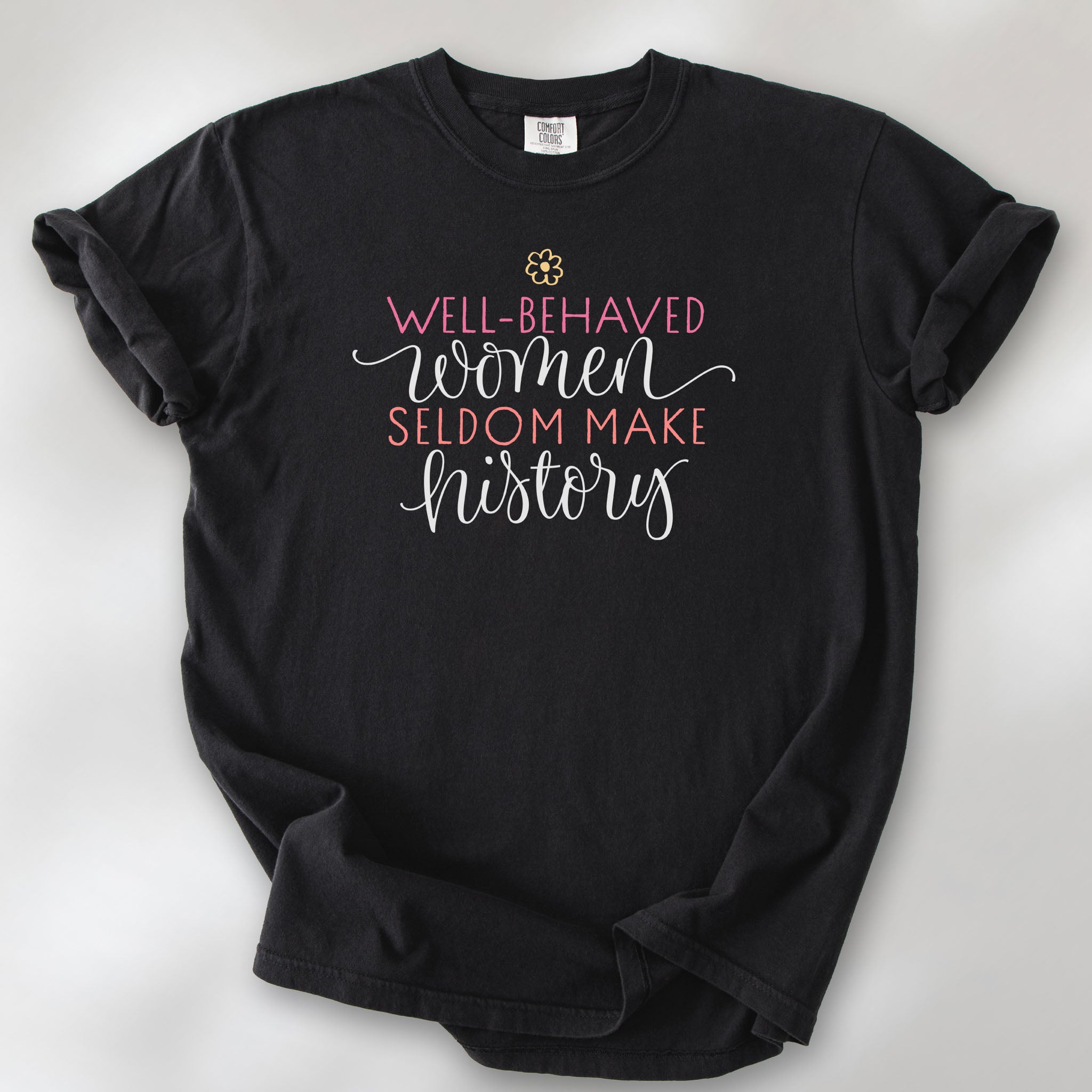 Black feminist t-shirt with colorful text that reads “Well-behaved women seldom make history” — empowering women’s rights shirt and activist apparel.