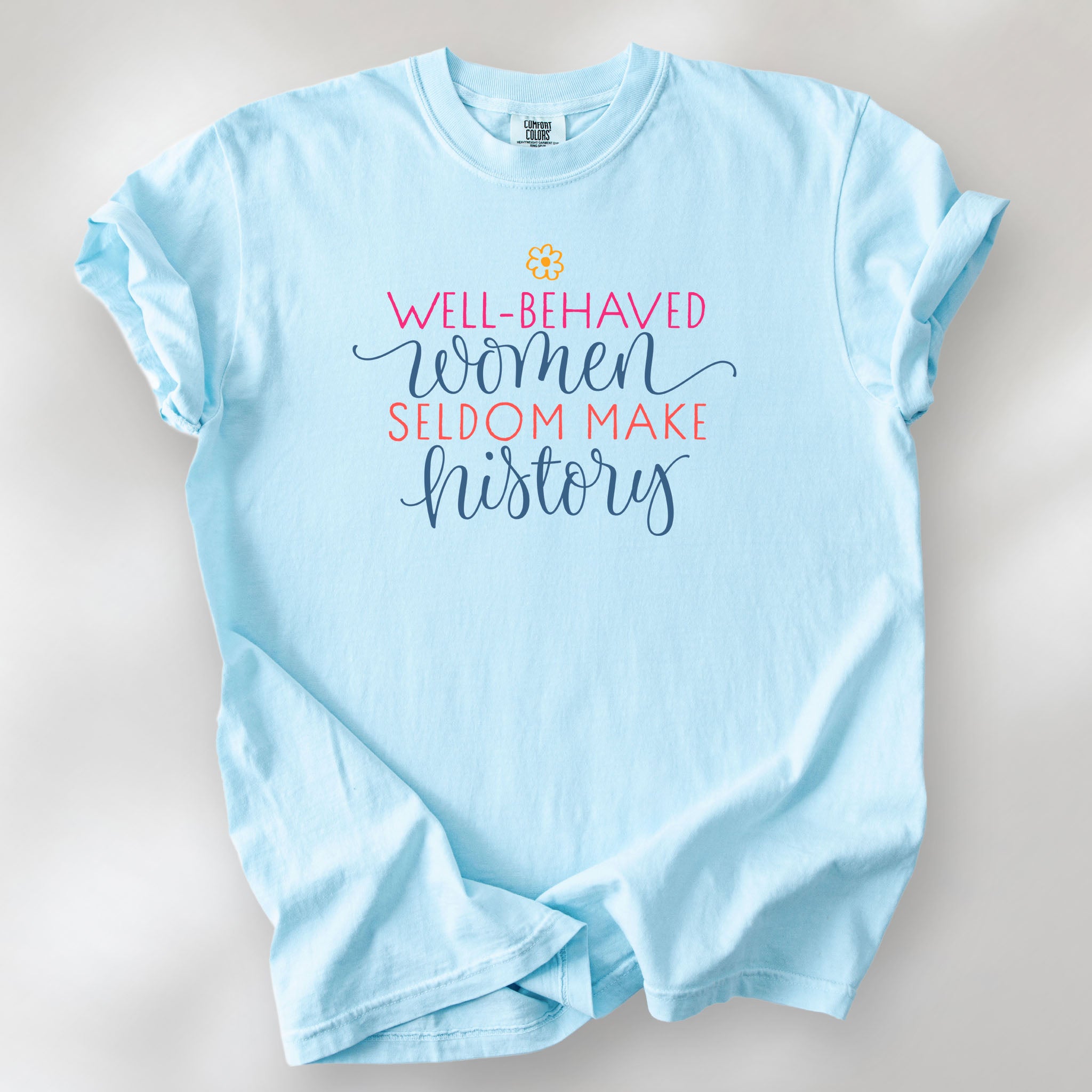 Chambray feminist t-shirt with colorful text that reads “Well-behaved women seldom make history” — empowering women’s rights shirt and activist apparel.
