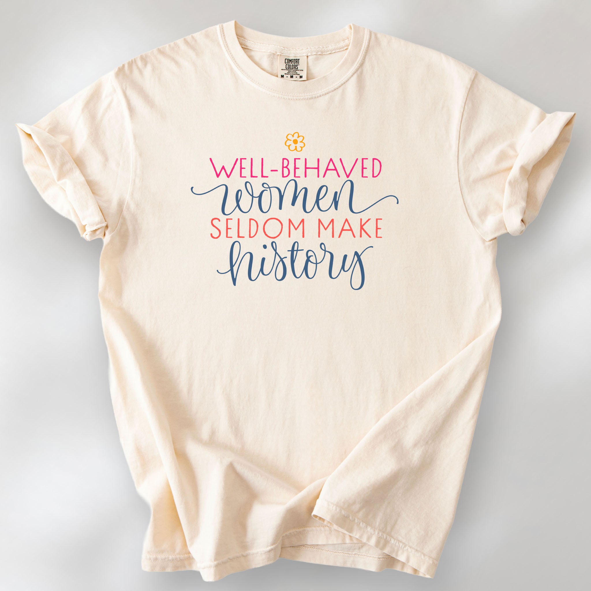 Ivory feminist t-shirt with colorful text that reads “Well-behaved women seldom make history” — empowering women’s rights shirt and activist apparel.