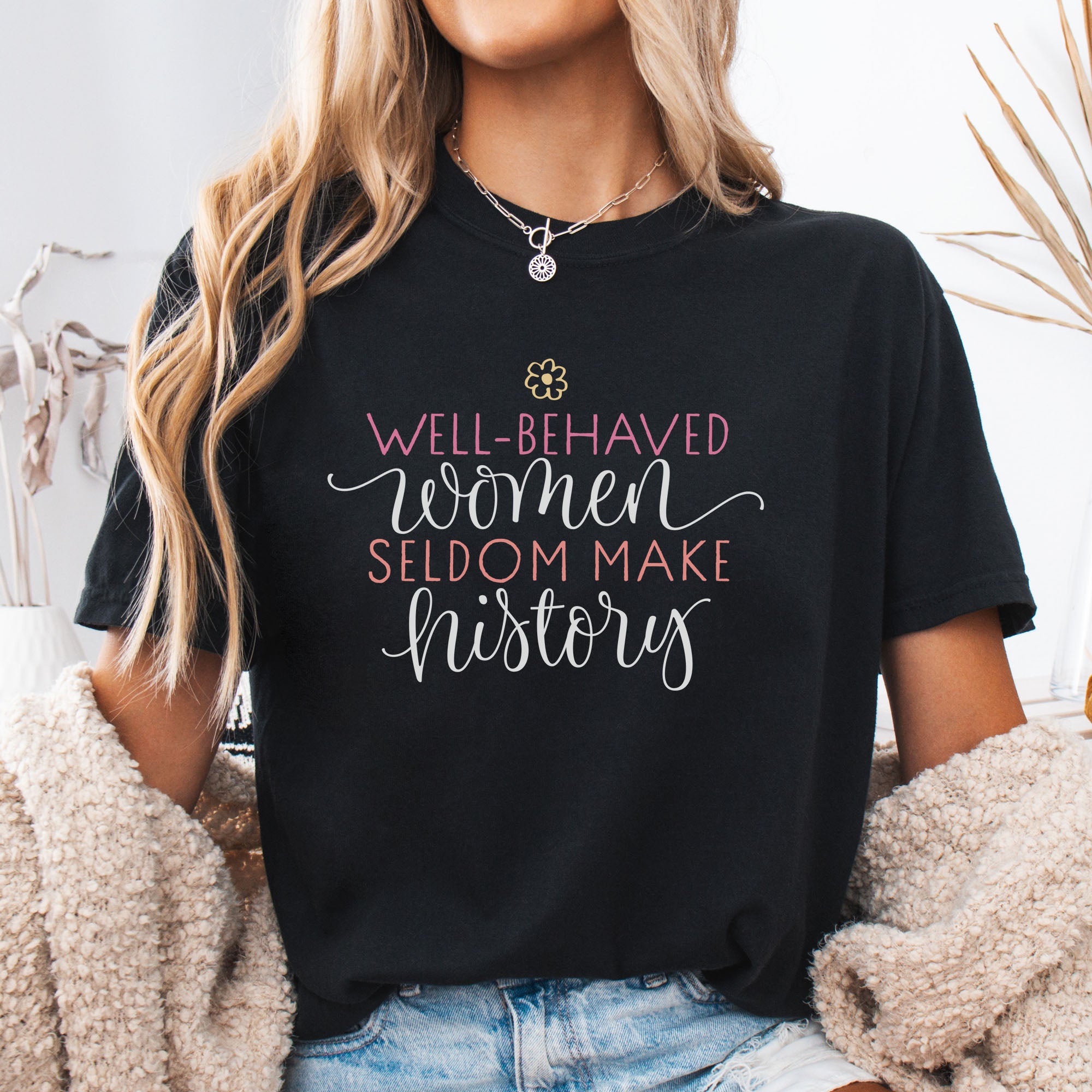 Female model wearing black feminist t-shirt with colorful text that reads “Well-behaved women seldom make history” — empowering women’s rights shirt and activist apparel.