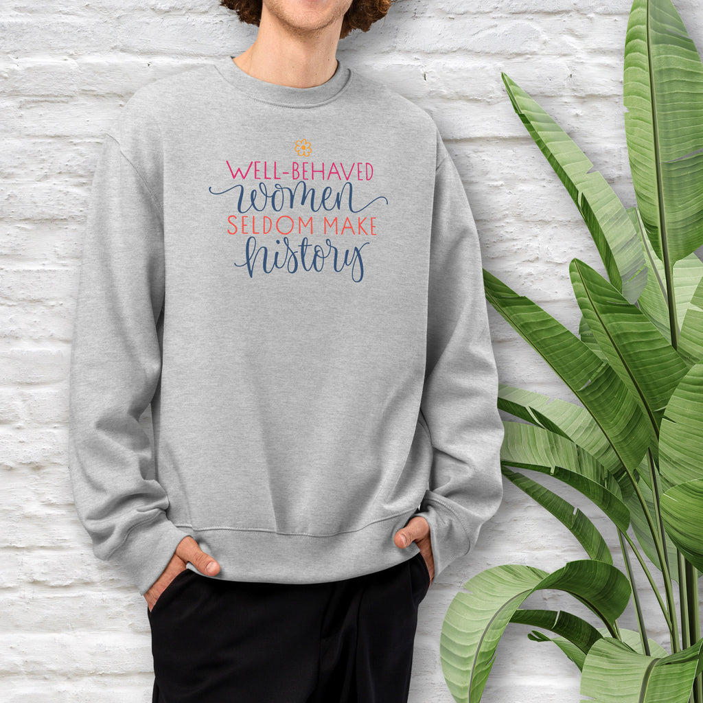 Male model wearing athletic heather grey crewneck sweatshirt with stylized text graphic that reads "well-behaved women seldom make history".