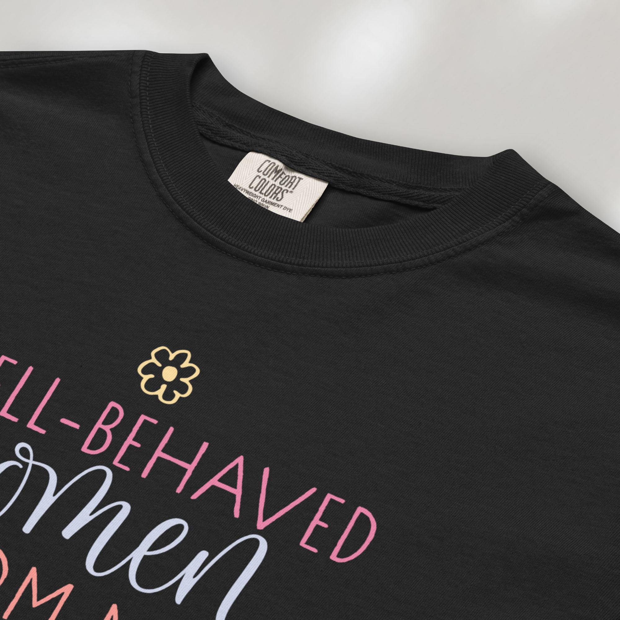 Closeup detail of black t-shirt with graphic styled text that reads "well-behaved women seldom make history."