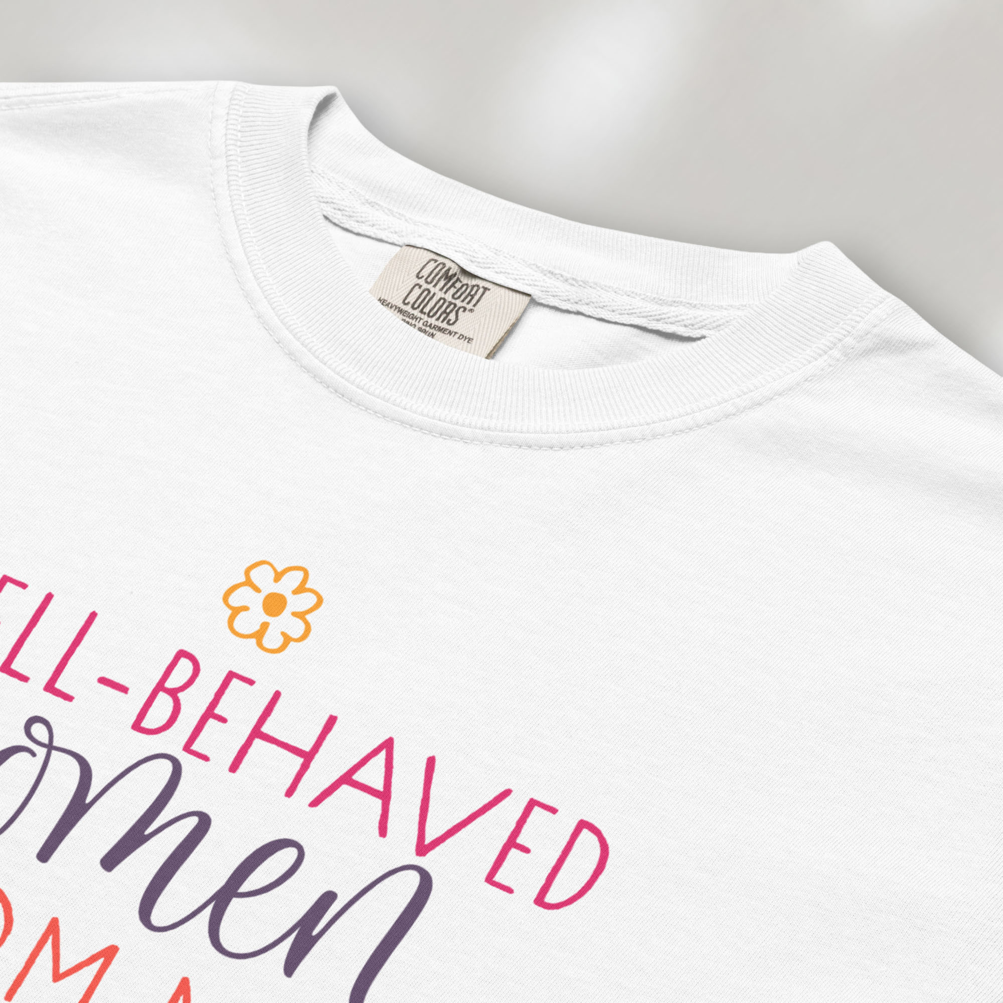 Closeup detail of white t-shirt with graphic styled text that reads "well-behaved women seldom make history."