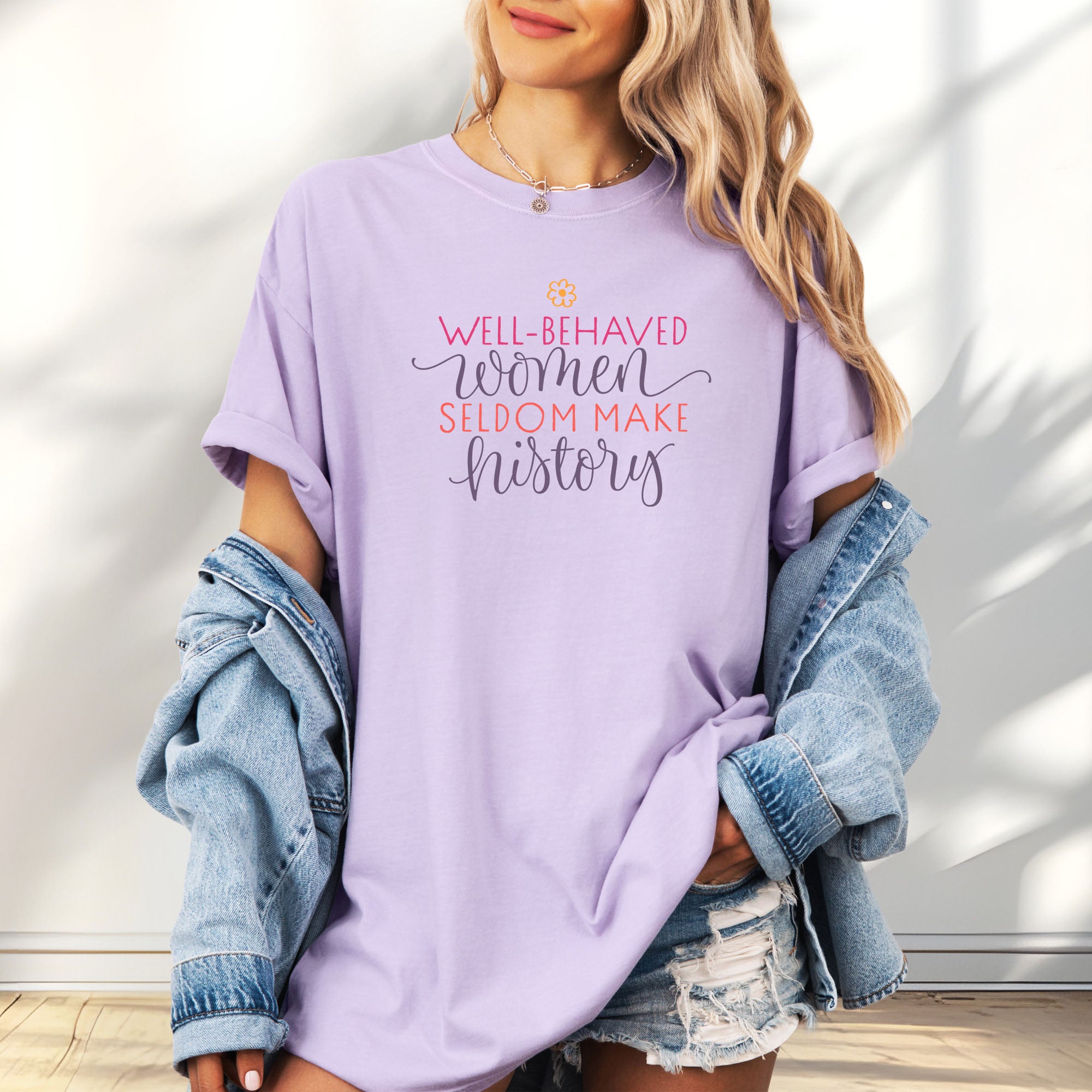 Female model wearing oversized orchid t-shirt with graphic styled text that reads "well-behaved women seldom make history."