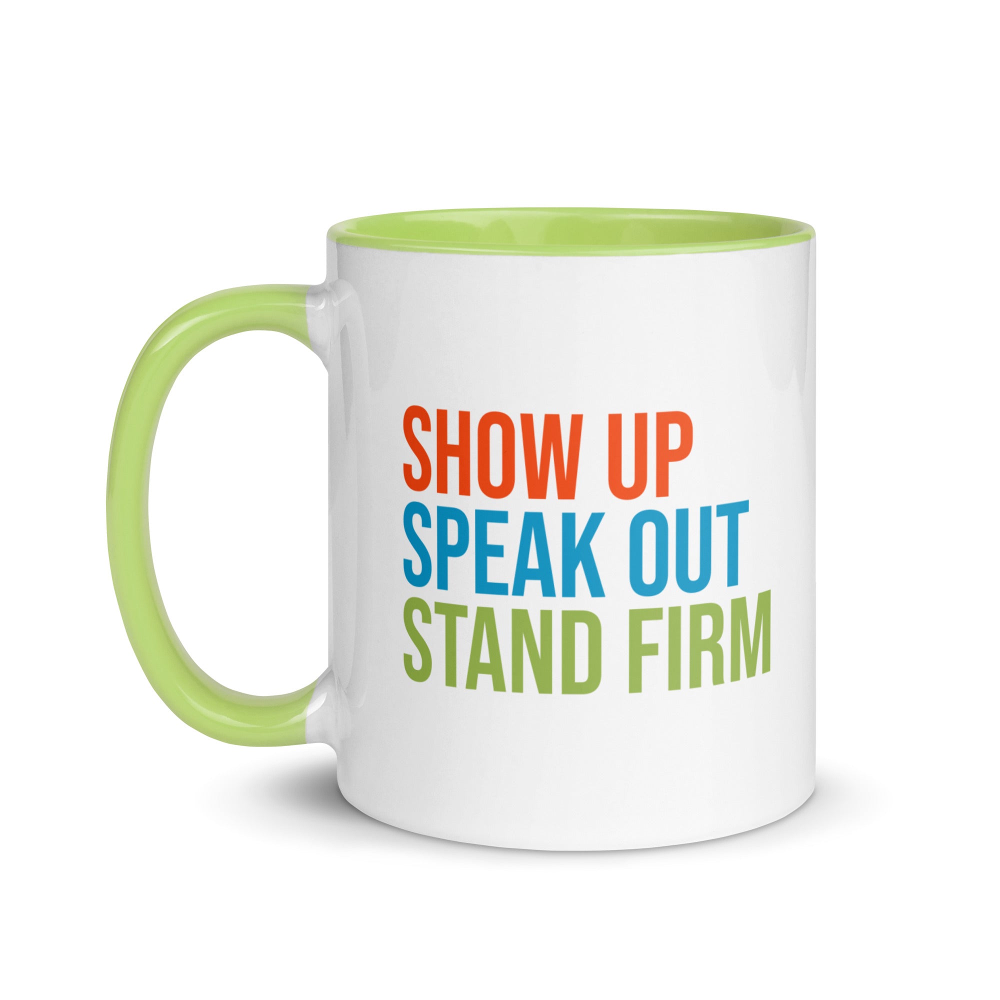 Coffee mug with bright green handle and inside with text on one side that reads "show up, speak out, stand firm." The other side, not shown in photo, reads "democracy doesn't defend itself."