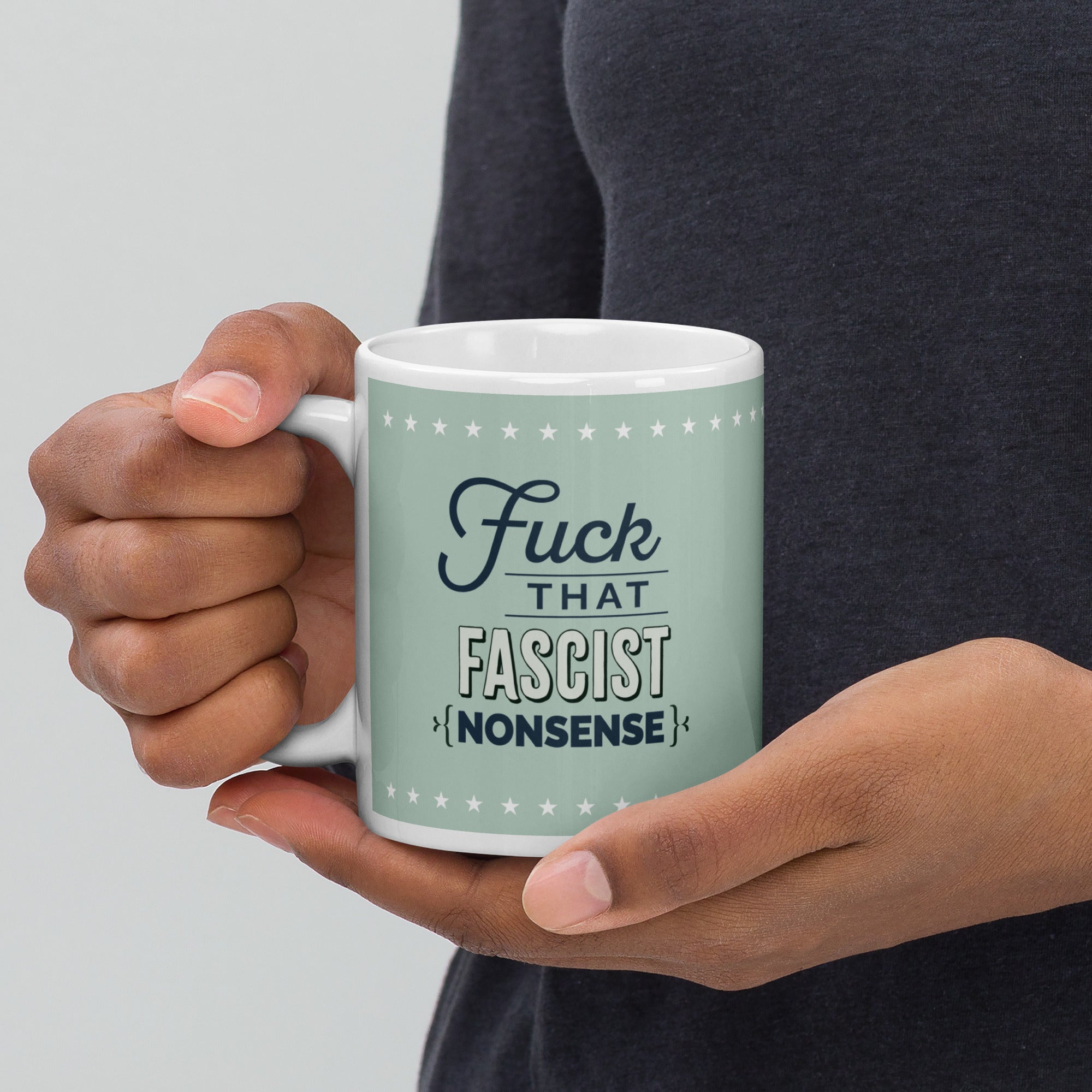 Person holding mug with graphic on mint green background and navy styled text block that reads "fuck that fascist nonsense." 
