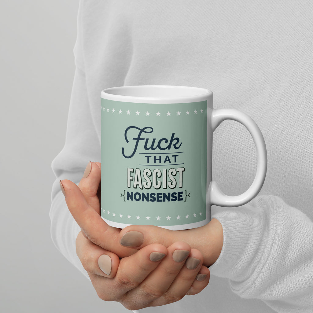 Person holding mug with graphic on mint green background and navy styled text block that reads "fuck that fascist nonsense." 