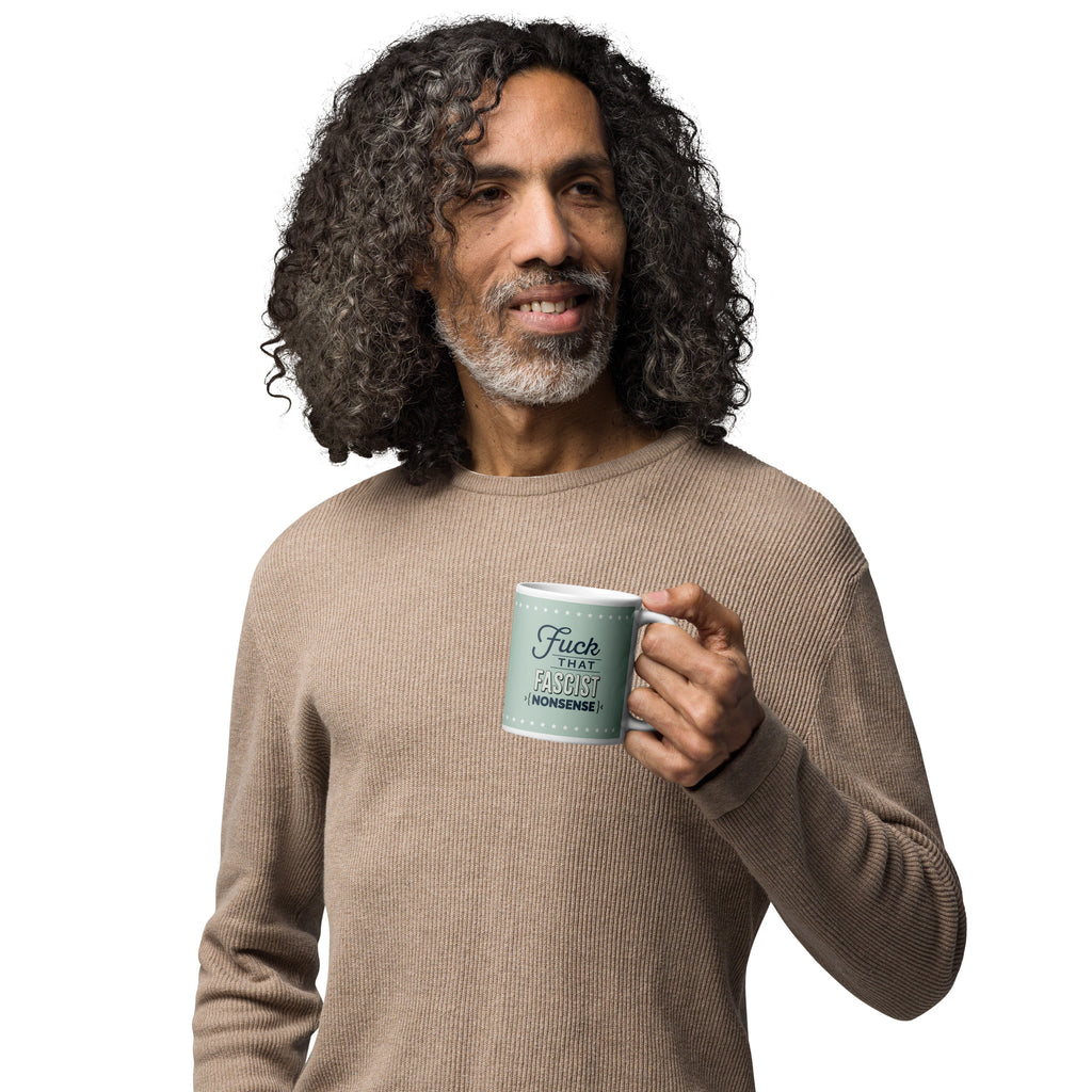 Person holding mug with graphic on mint green background and navy styled text block that reads "fuck that fascist nonsense." 