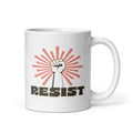 11 ounce coffee mug with a raised fist graphic in front of a coral burst, and bold retro-styled text that says "resist."