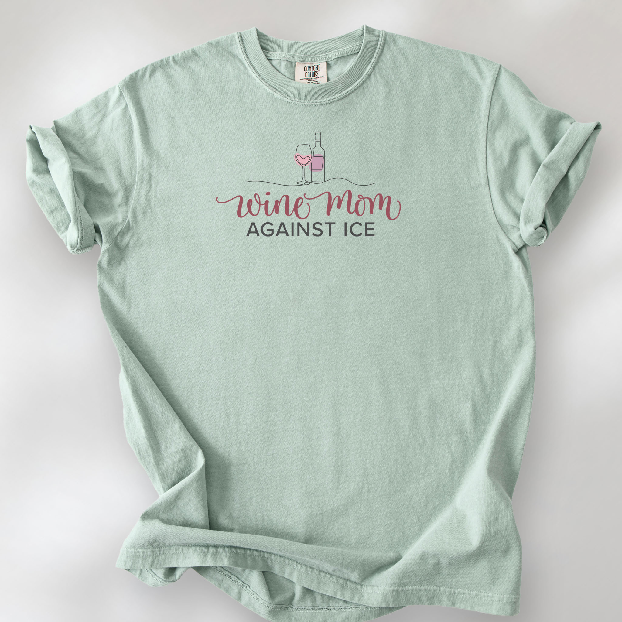 Bay t-shirt featuring the text “Wine Mom Against ICE” with a minimalist illustration of a wine bottle and glass above the lettering.