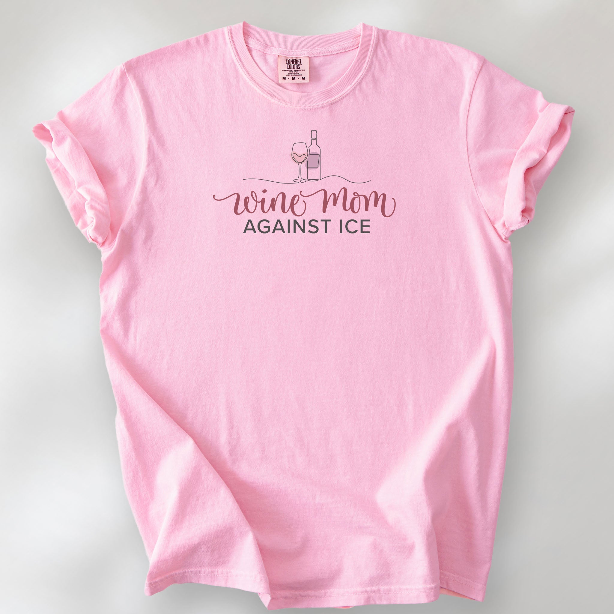 Blossom t-shirt featuring the text “Wine Mom Against ICE” with a minimalist illustration of a wine bottle and glass above the lettering.