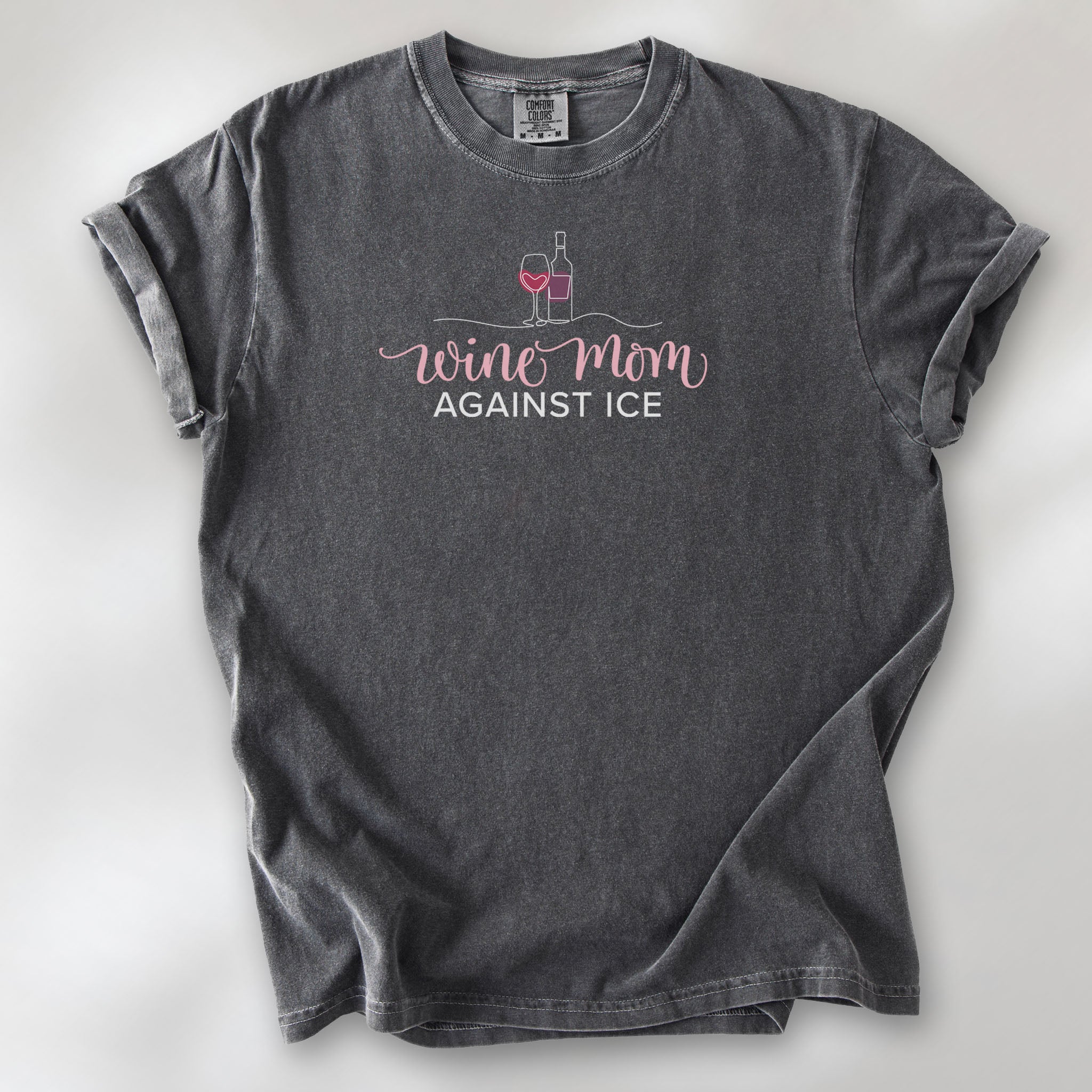 Pepper t-shirt featuring the text “Wine Mom Against ICE” with a minimalist illustration of a wine bottle and glass above the lettering.