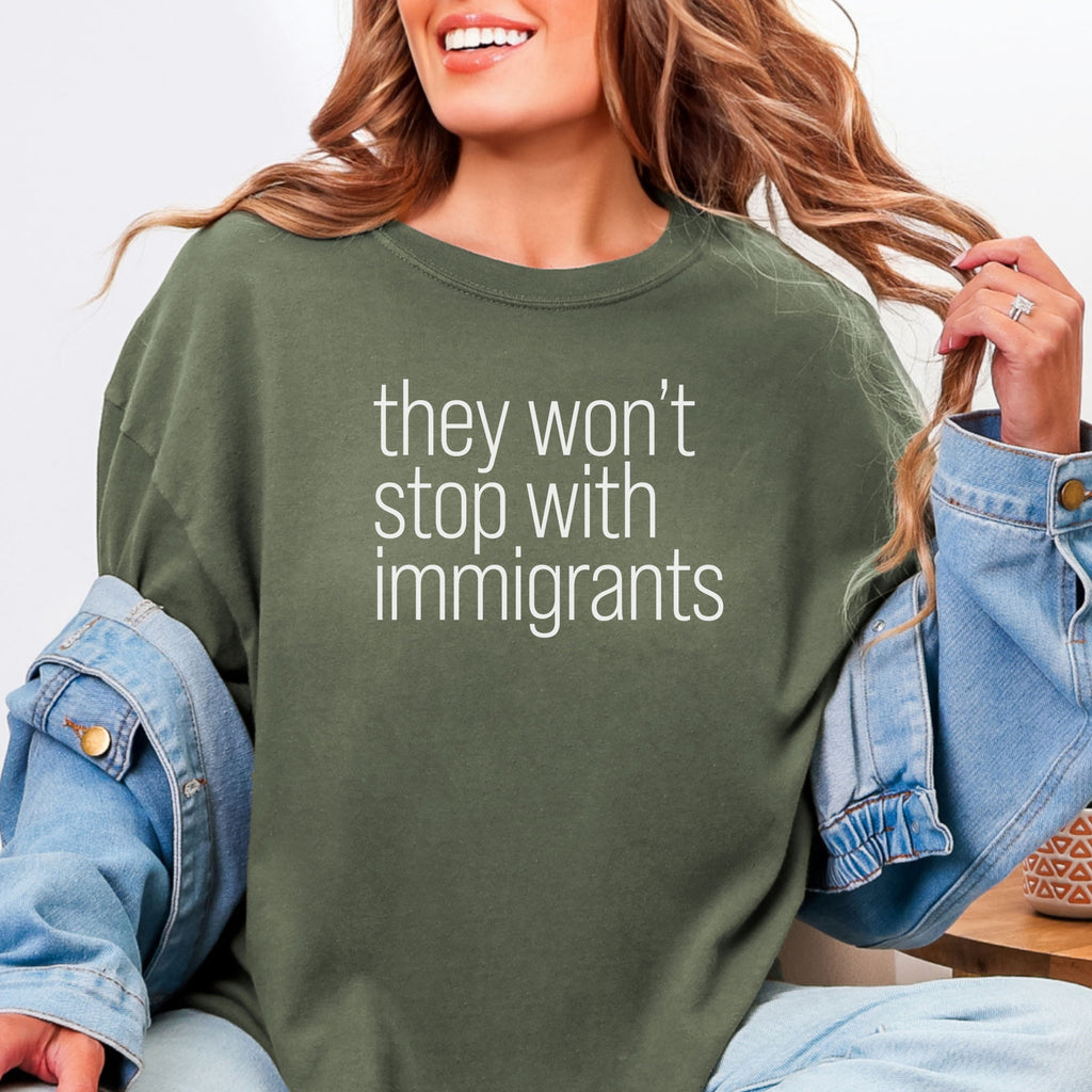 Female model wearing sage comfort colors tshirt with anti-ICE, anti-trump, anti-tyranny message that reads "they won't stop with immigrants."
