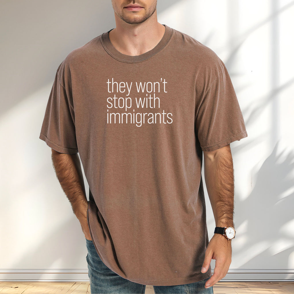 Male model wearing espresso comfort colors tshirt with anti-ICE, anti-trump, anti-tyranny message that reads "they won't stop with immigrants."