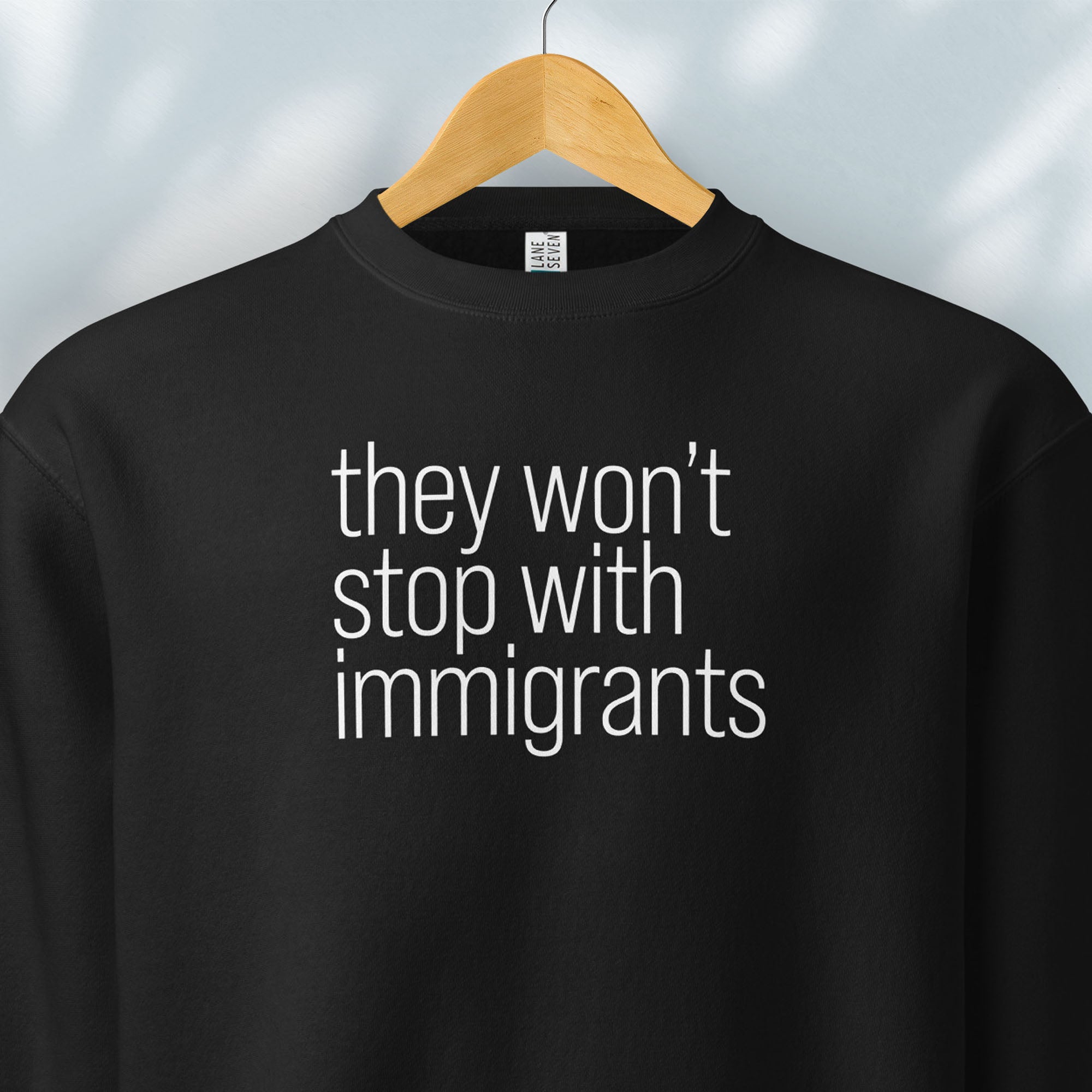 Hanging black sweatshirt with anti-ICE, anti-trump, anti-tyranny message that reads "they won't stop with immigrants."