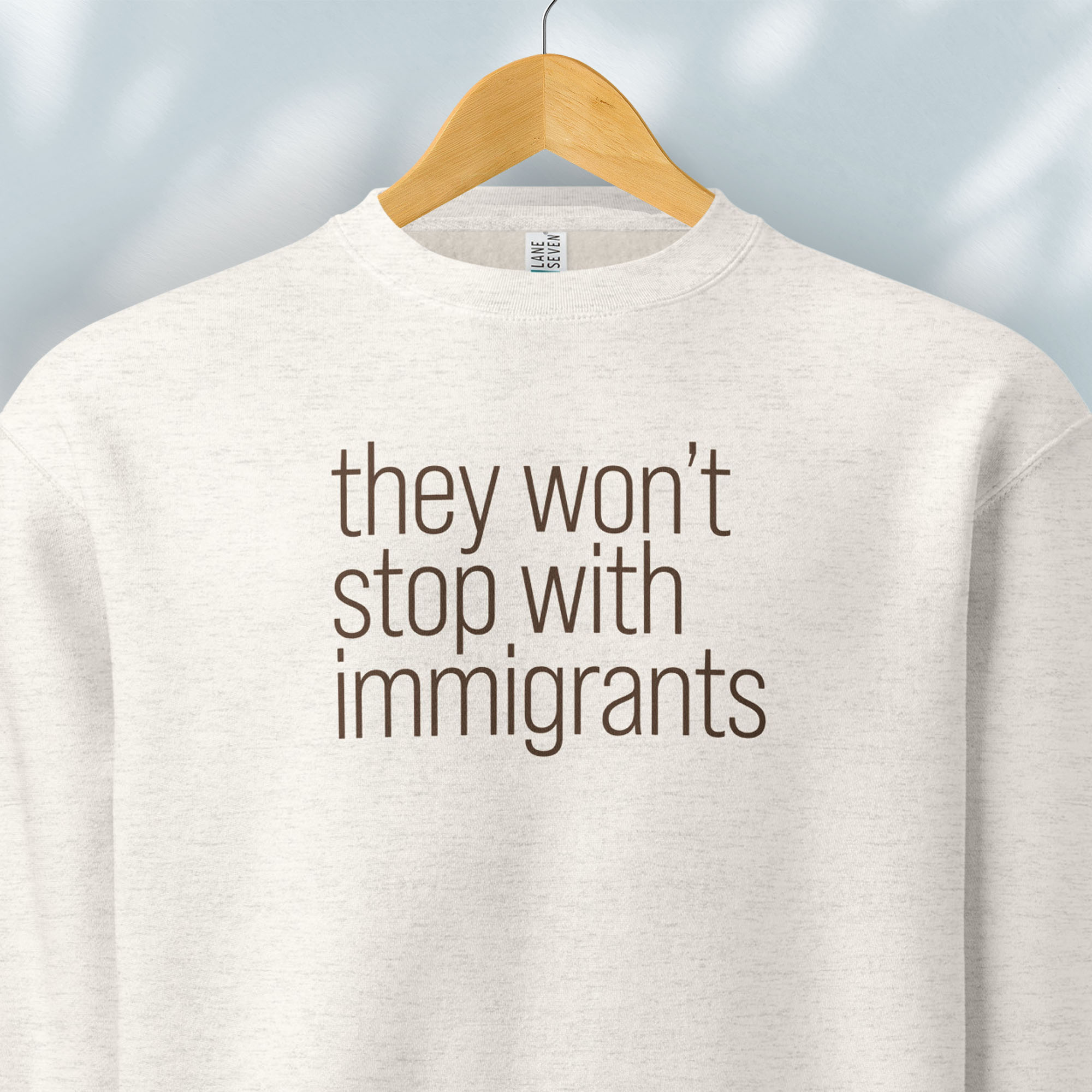 Hanging oatmeal sweatshirt with anti-ICE, anti-trump, anti-tyranny message that reads "they won't stop with immigrants."