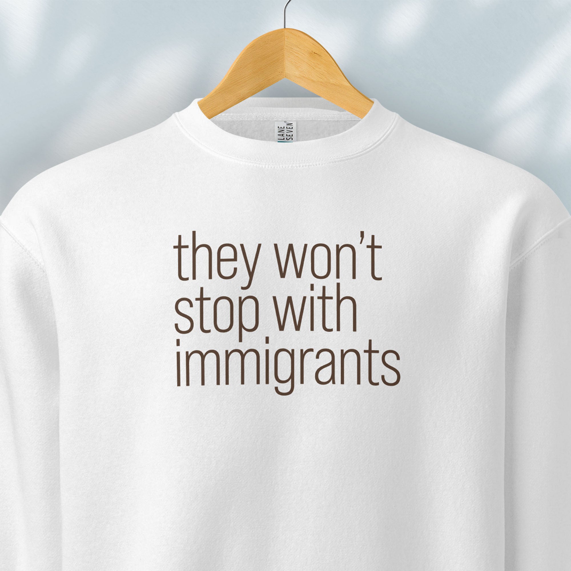 Hanging white sweatshirt with anti-ICE, anti-trump, anti-tyranny message that reads "they won't stop with immigrants."