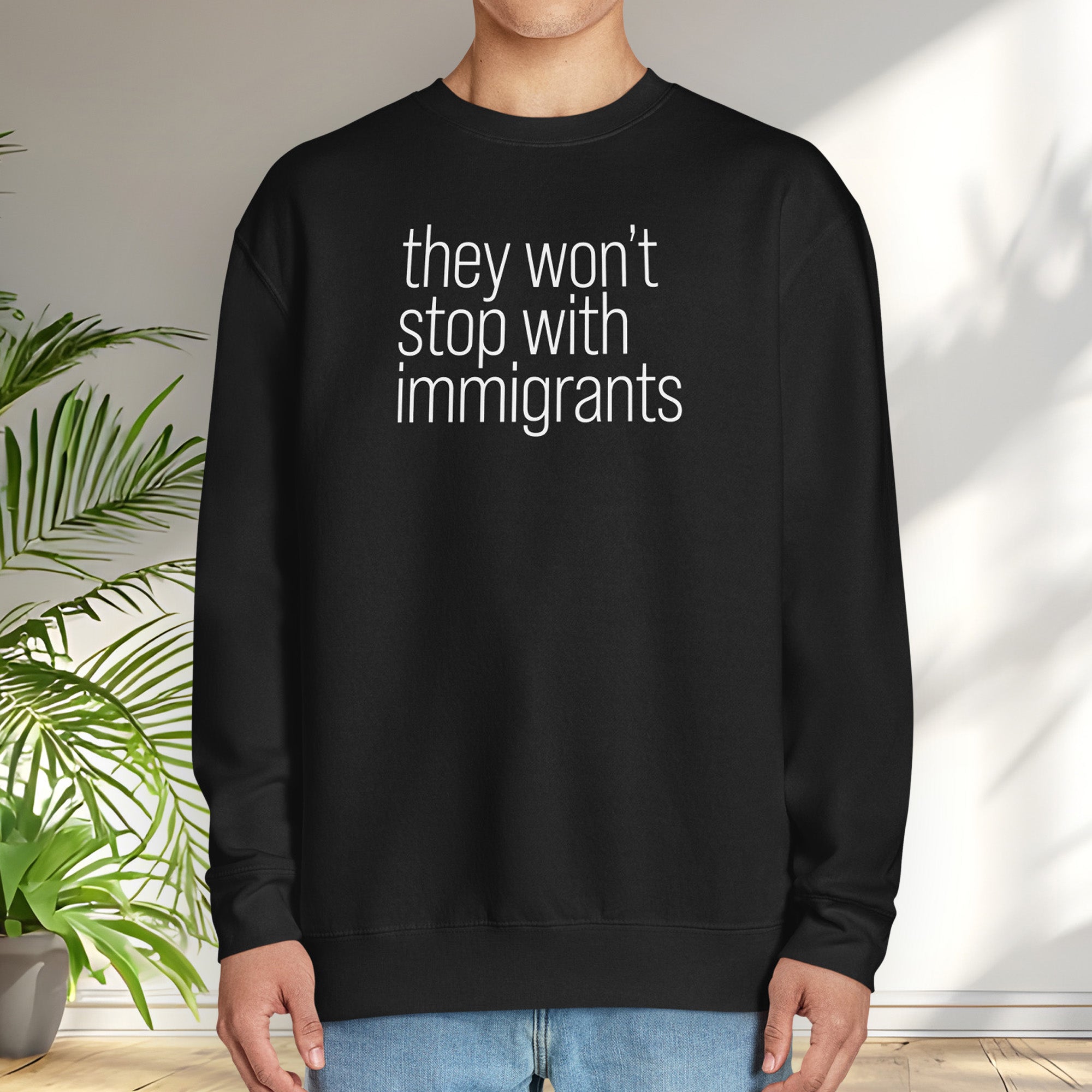 Male model wearing black sweatshirt with anti-ICE, anti-trump, anti-tyranny message that reads "they won't stop with immigrants."