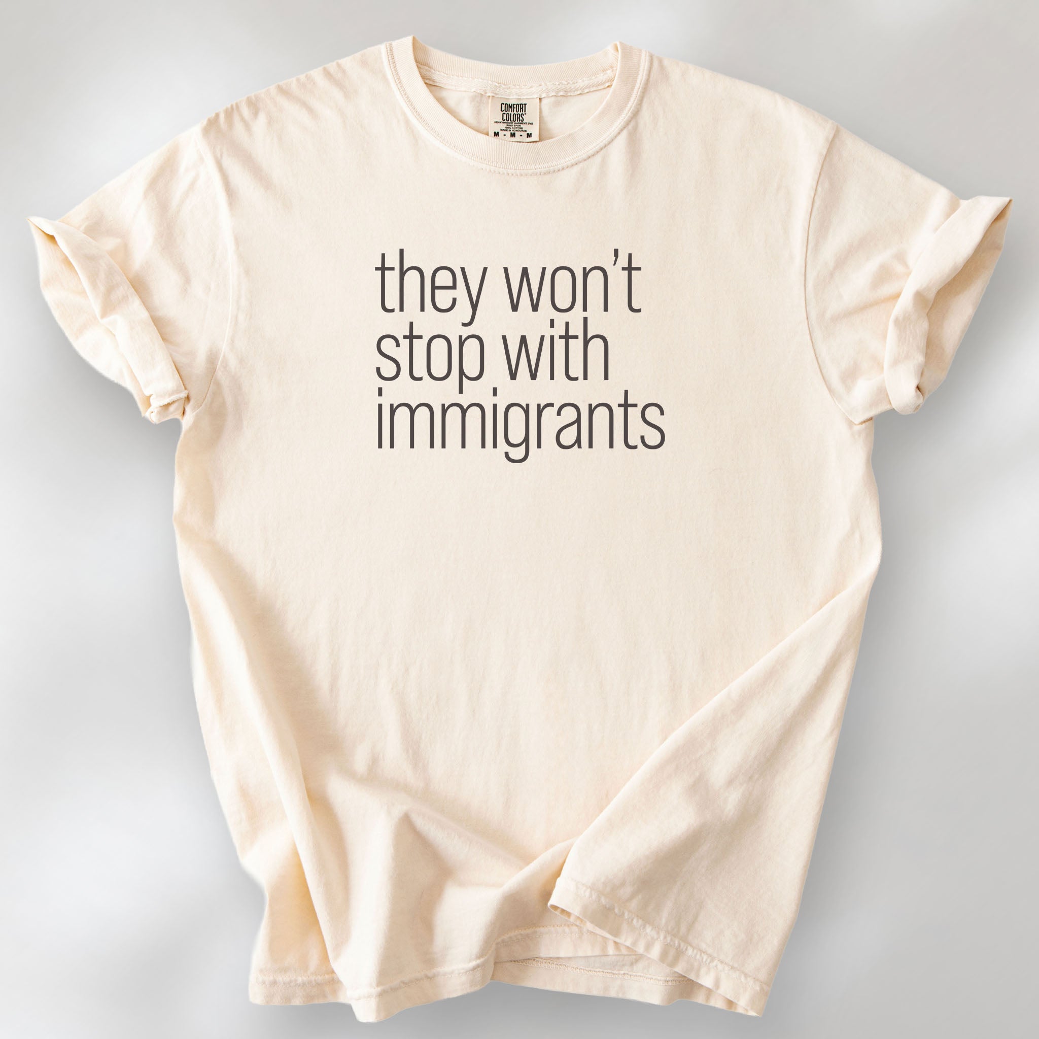 Ivory shirt with minimalist text that reads "they won't stop with immigrants."
