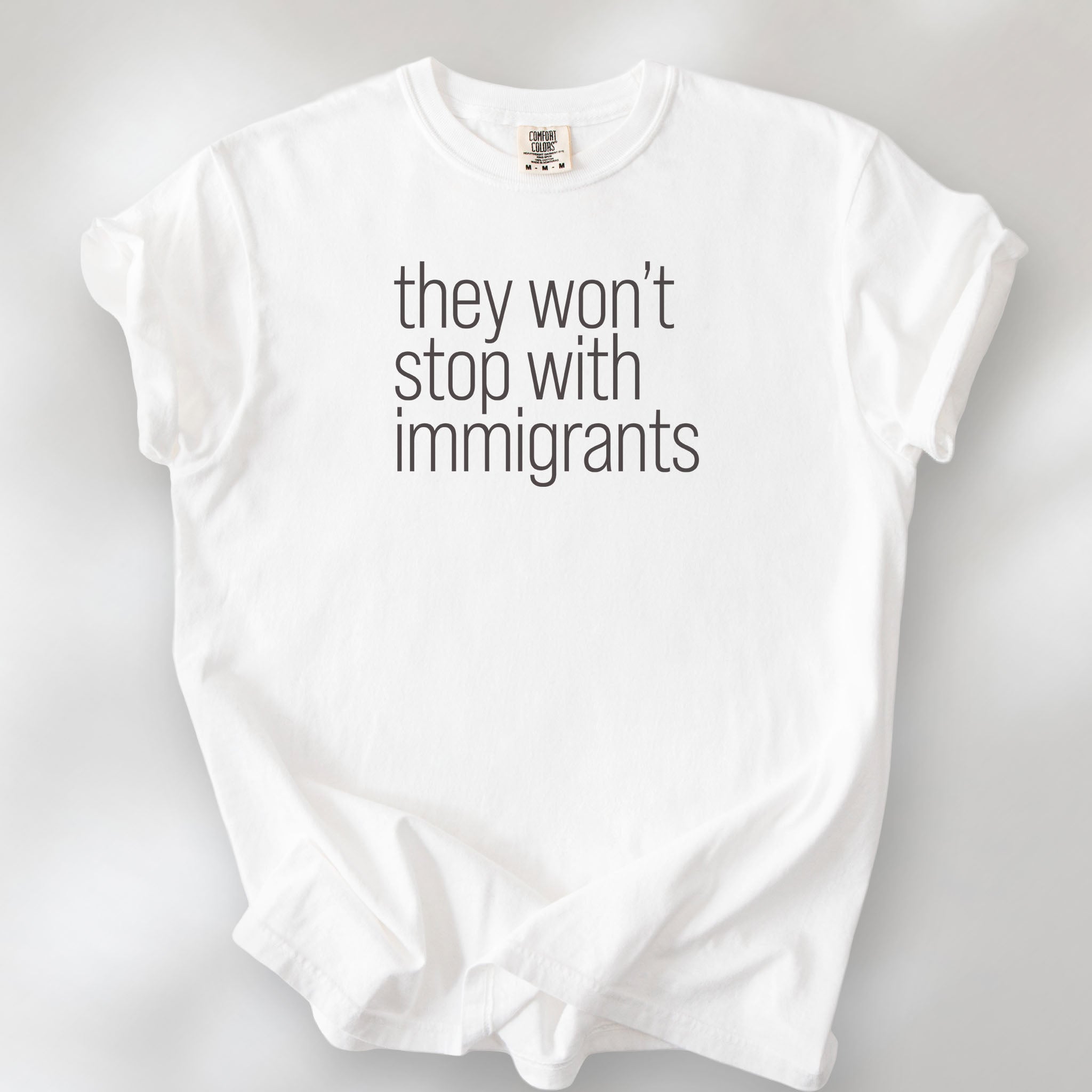 White shirt with minimalist text that reads "they won't stop with immigrants."